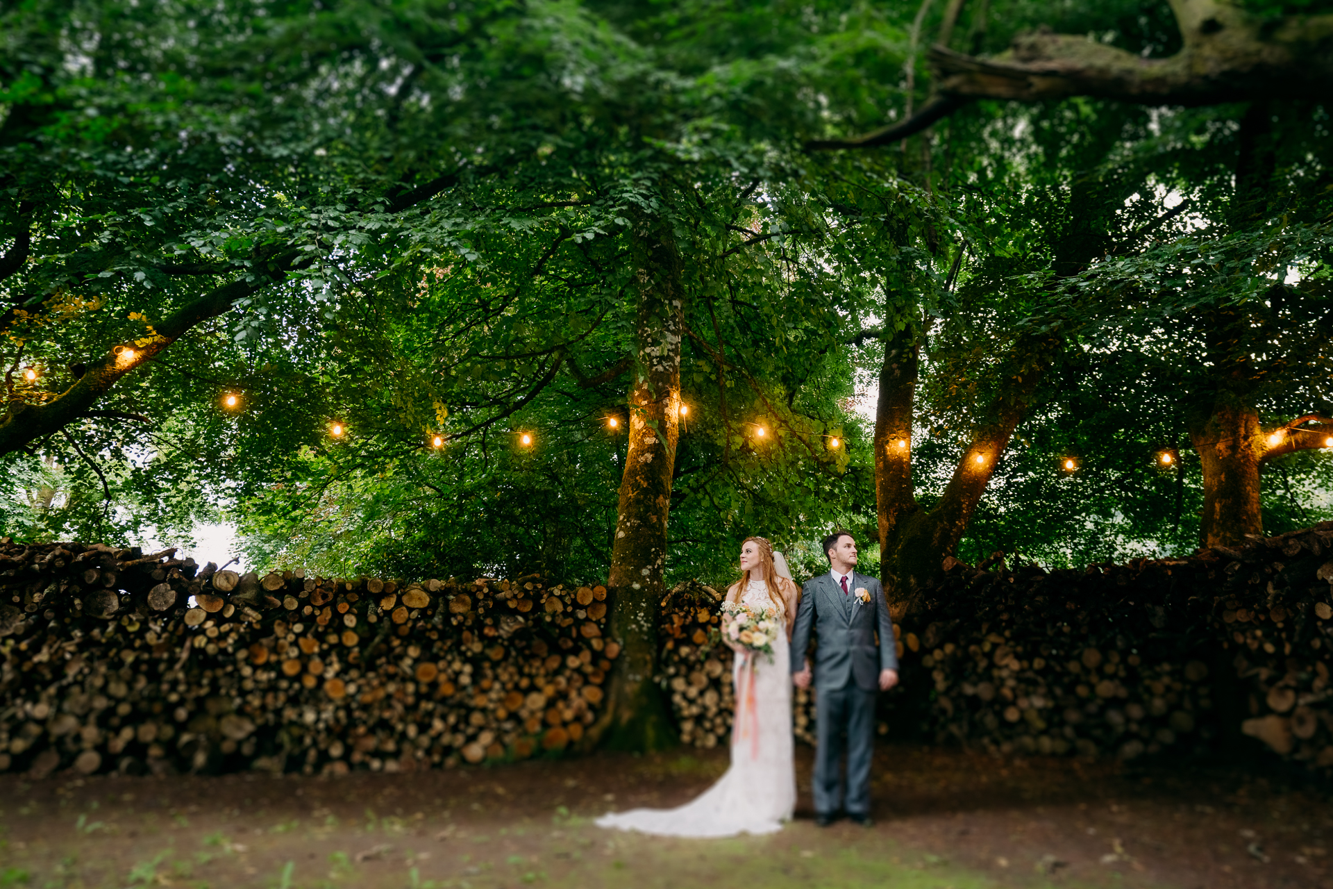 A man and woman posing for a picture under a tree