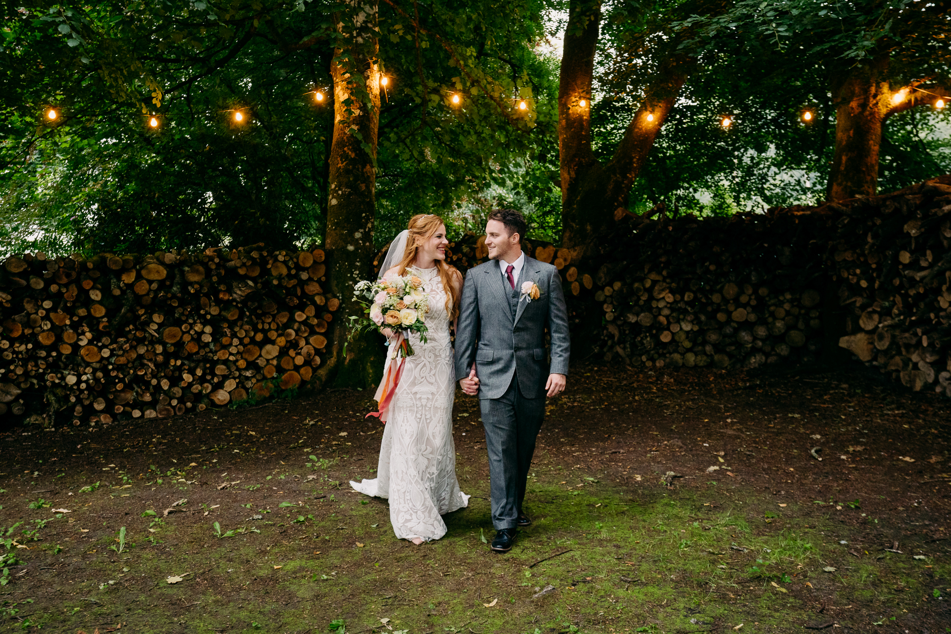 A man and woman walking down a path with lights on the side