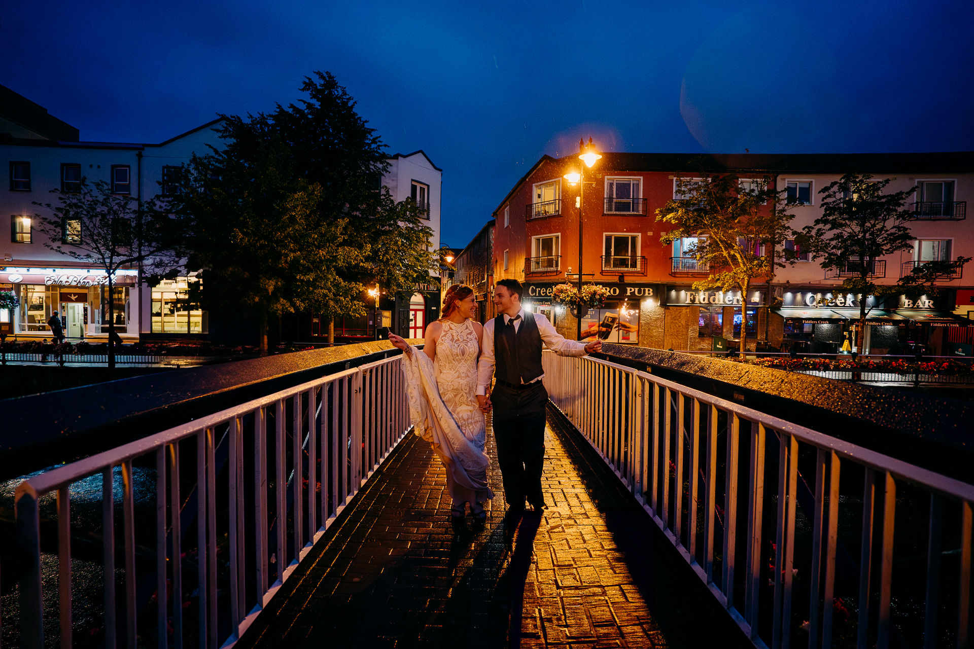 A man and woman walking on a bridge at night