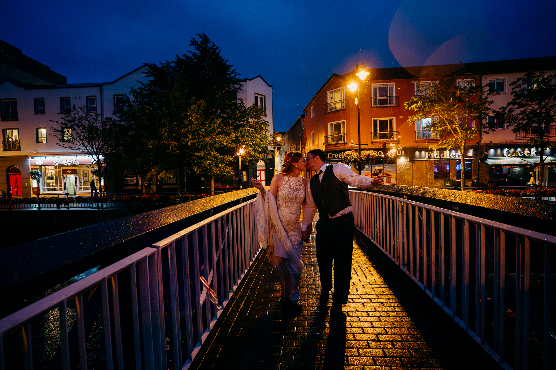 A man and woman kissing on a bridge at night