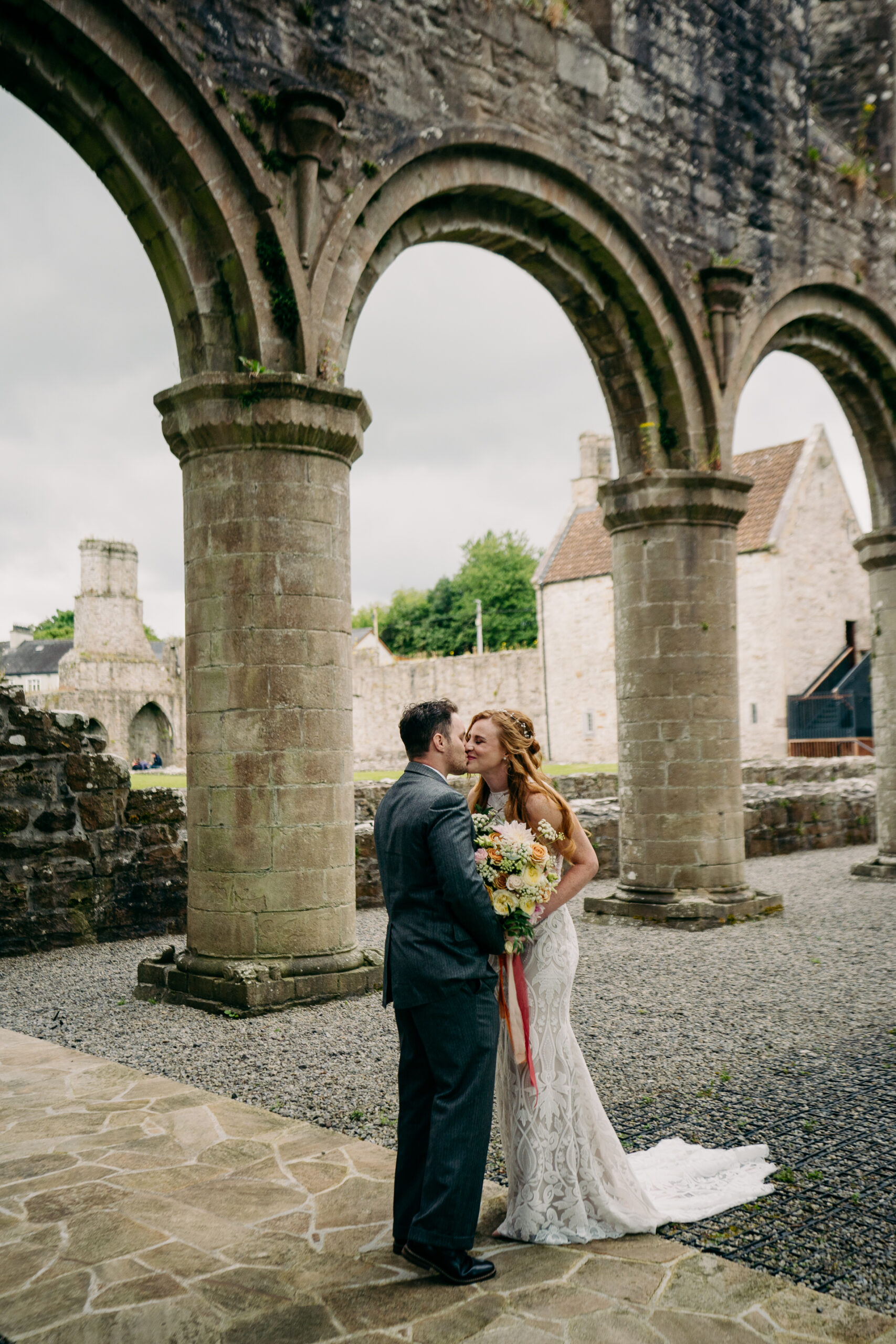 A man and woman kissing in front of a stone archway