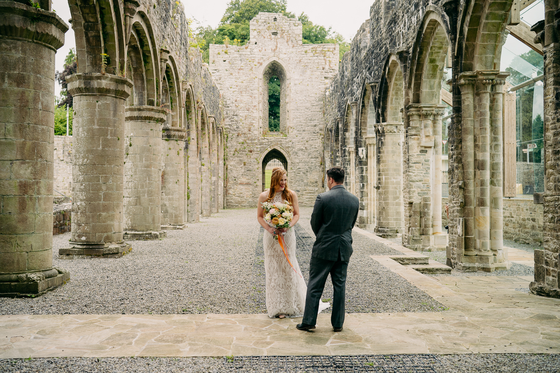 A man and woman walking in a stone courtyard with pillars and a building