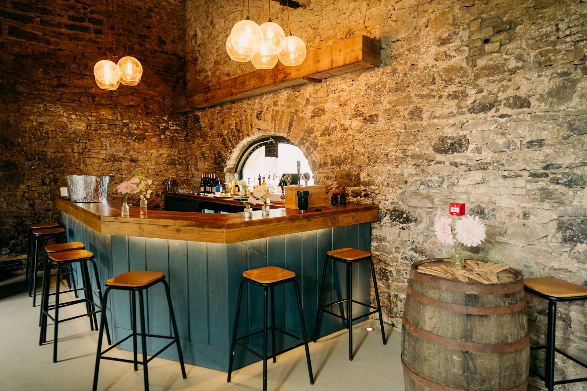 A bar with stools and a table with a barrel on it