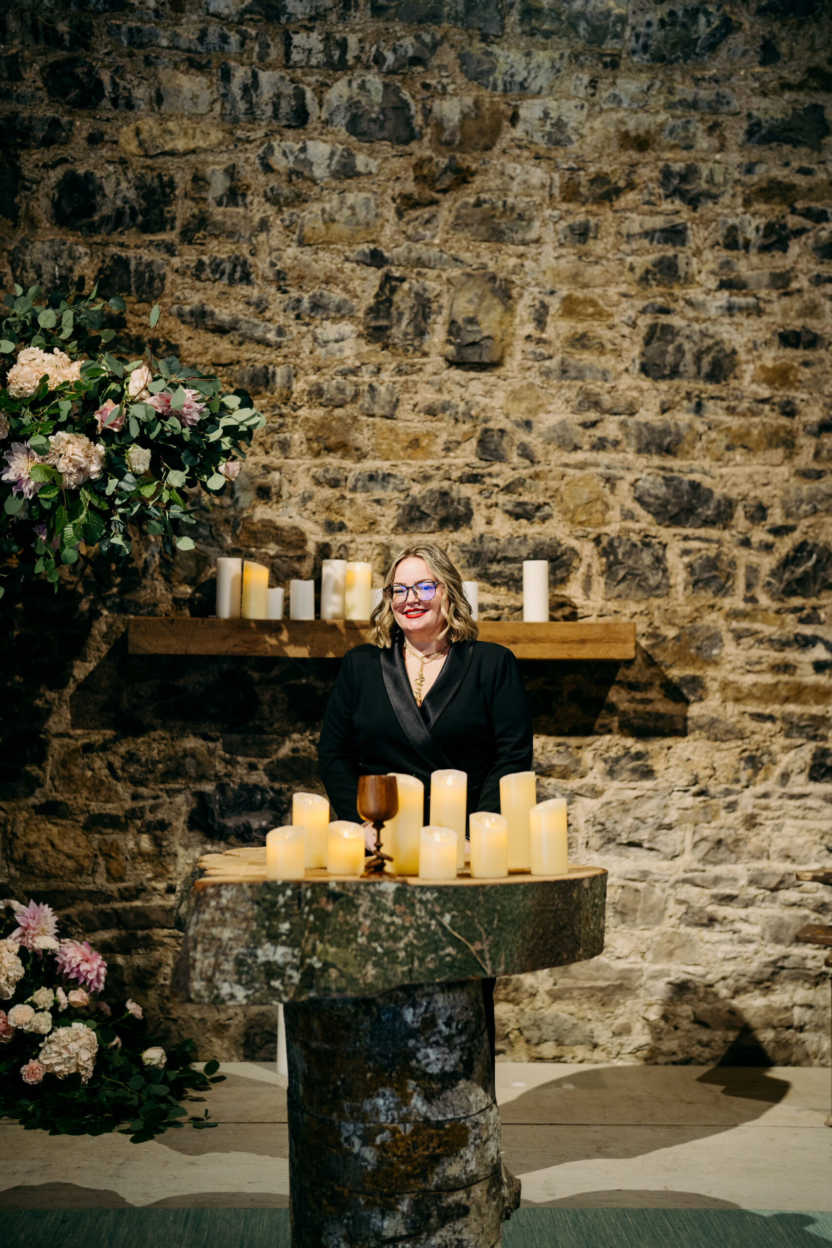 A person sitting at a table with candles and flowers