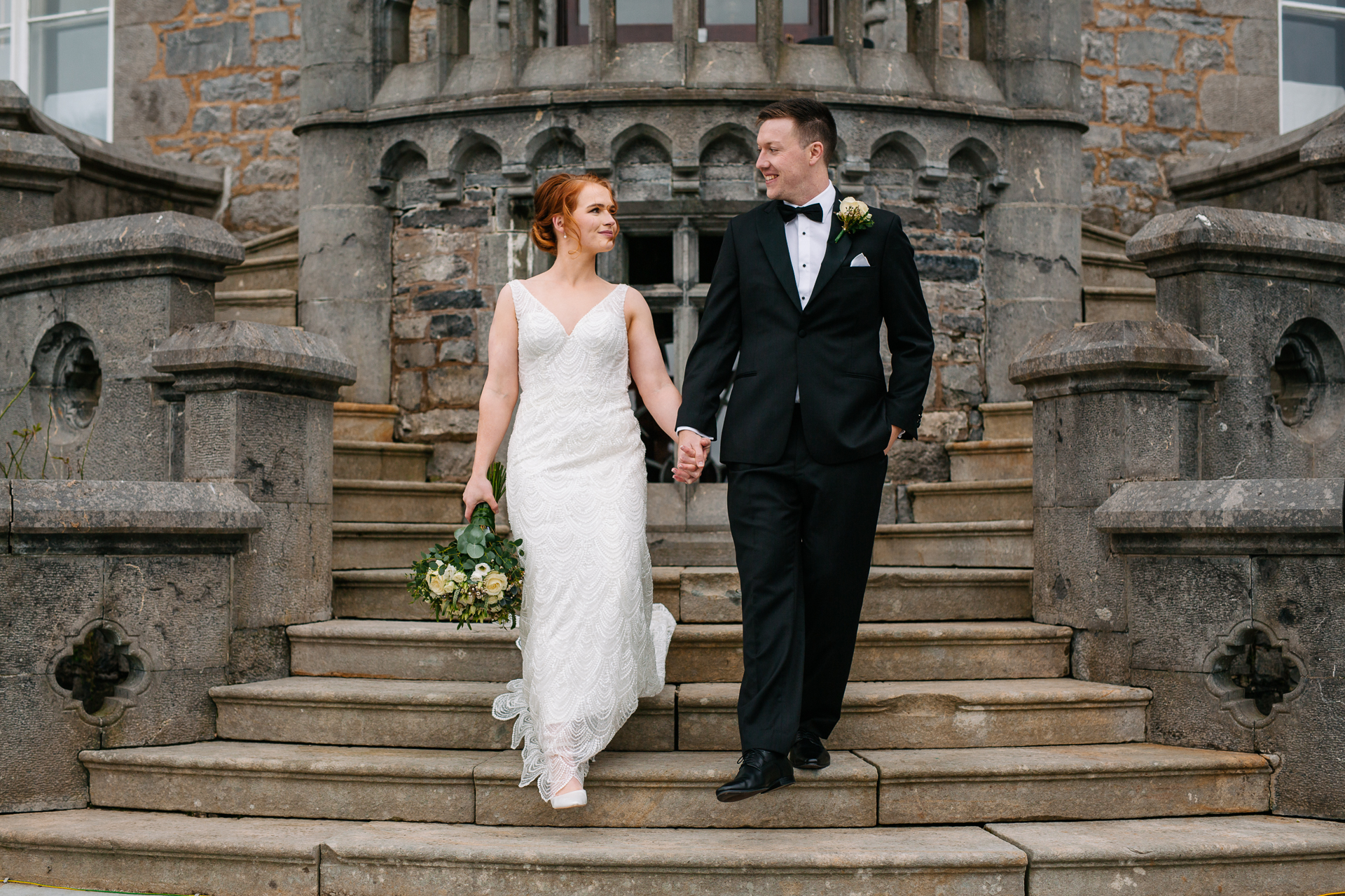 A man and woman in wedding attire walking up stairs