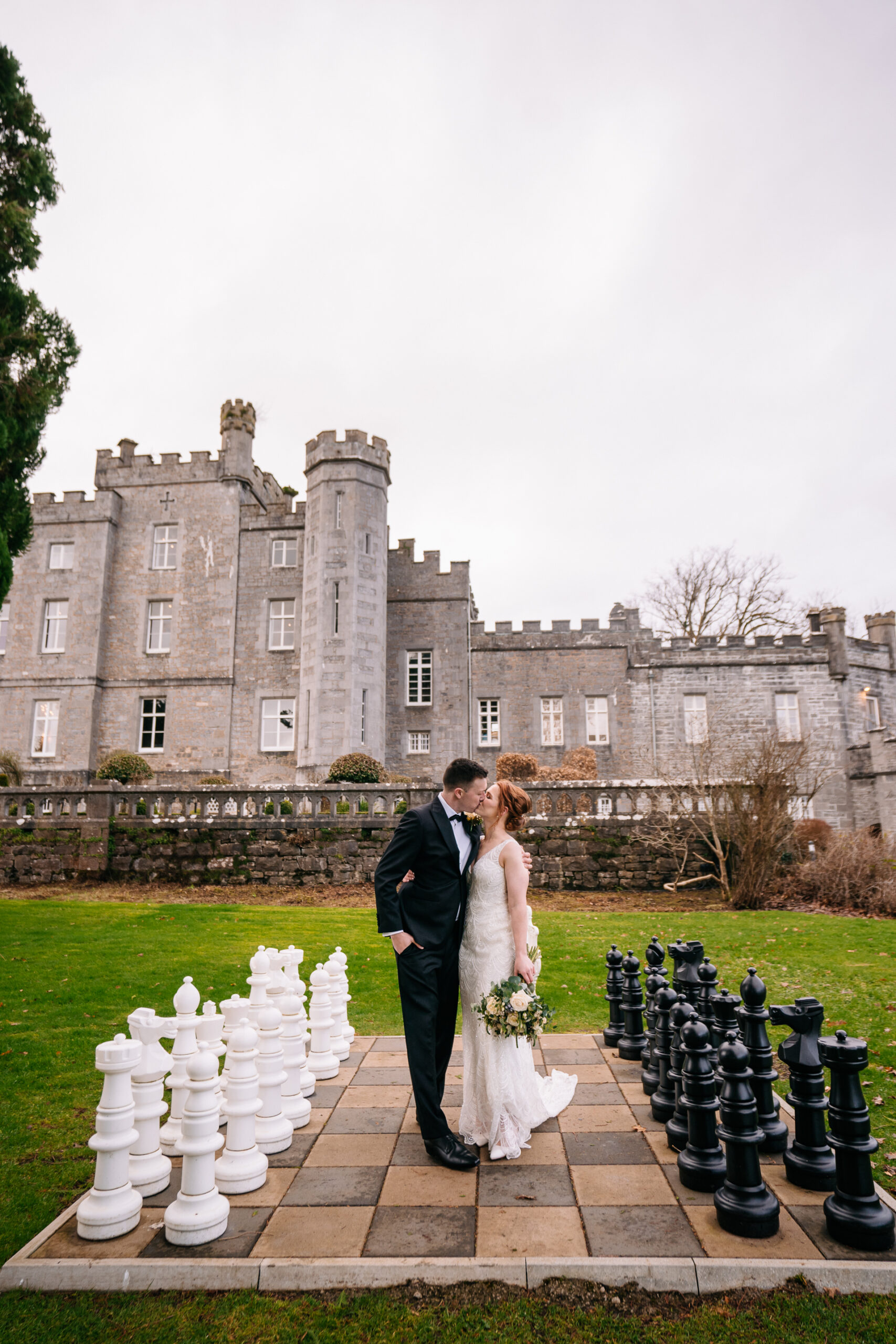 A man and woman kissing in front of a castle