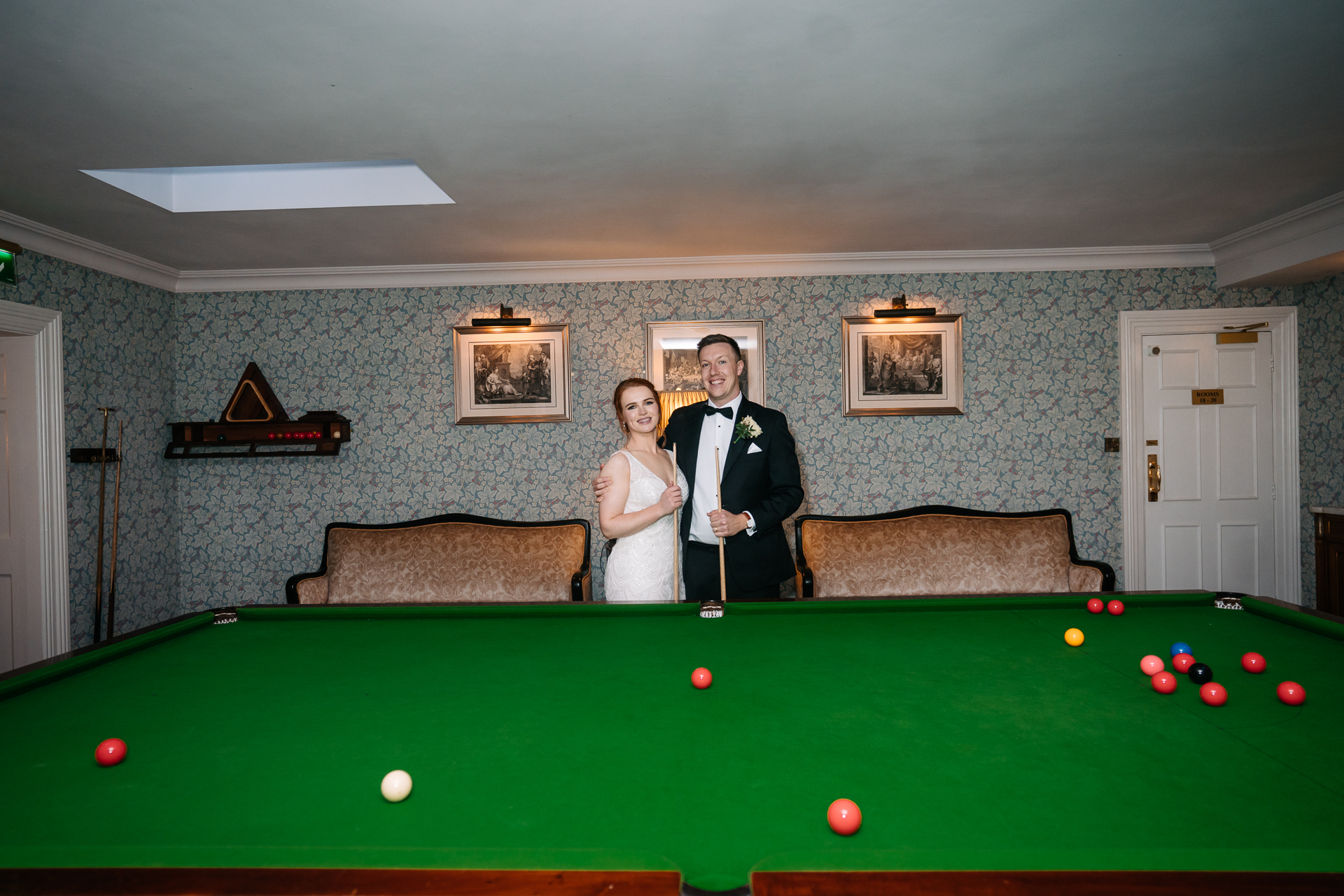 A man and woman in formal wear standing in front of a pool table