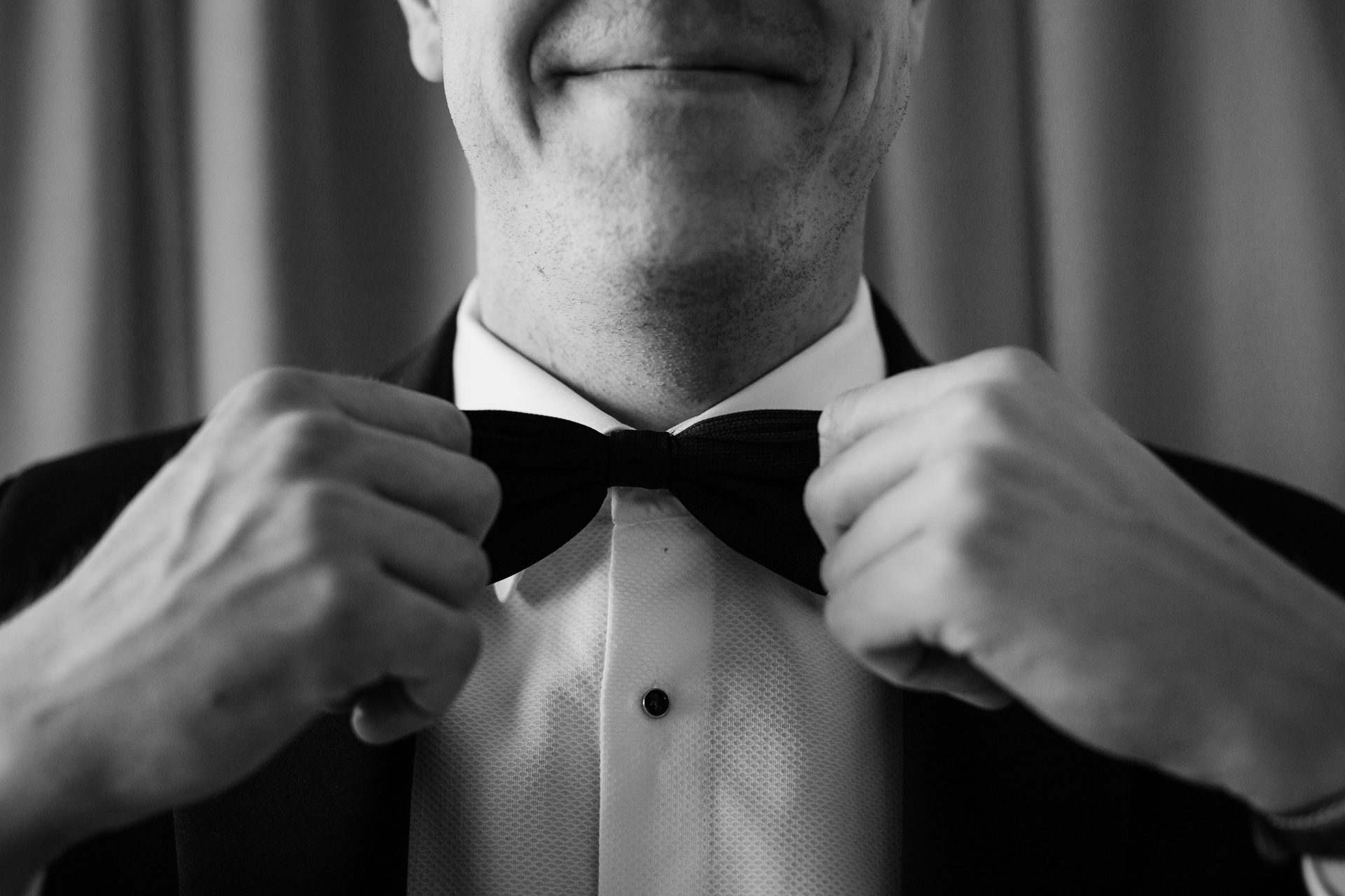 A man in a tuxedo tying his tie