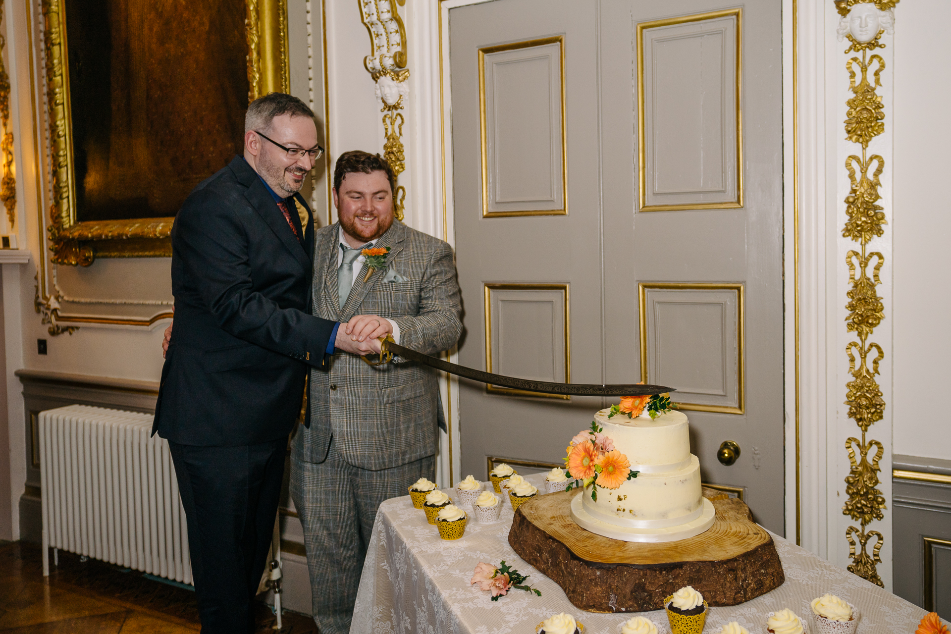 A beautifully decorated wedding cake and the cake-cutting ceremony of two grooms during their LGBT wedding at Markree Castle, Ireland.