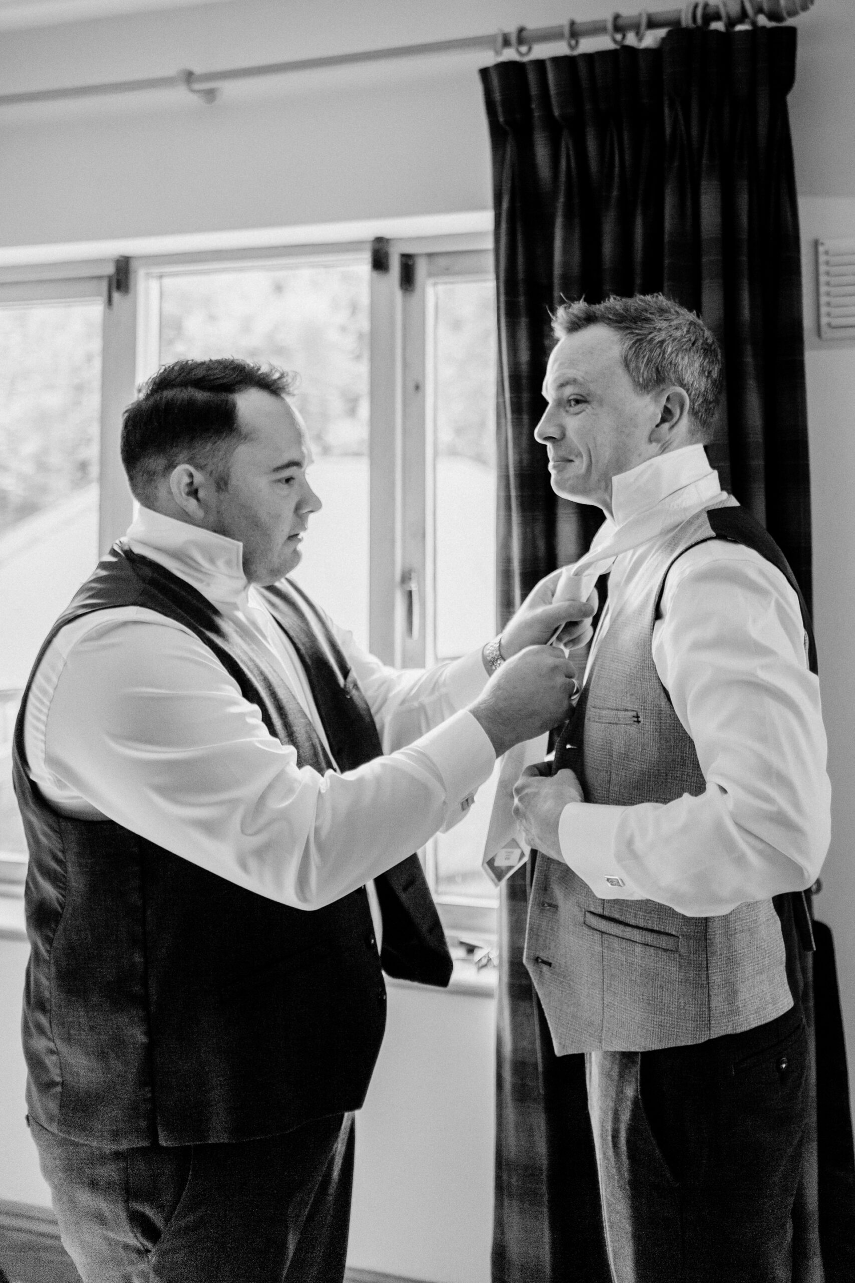 Groom adjusting his tie in the grand interiors of Powerscourt House in Wicklow.