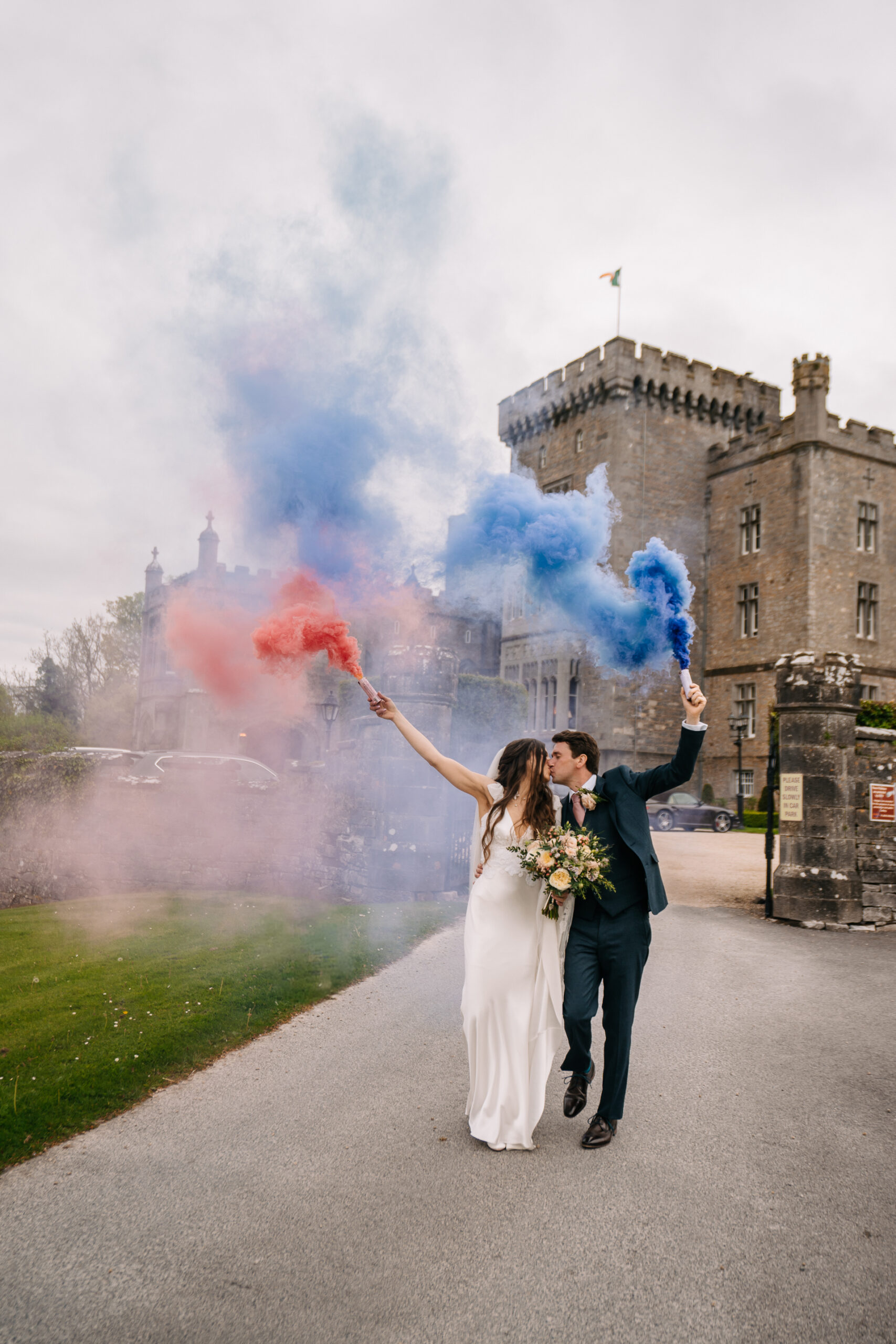 A newlywed couple celebrates their wedding day at Markree Castle, Ireland, with colorful smoke bombs, creating a breathtaking and cinematic moment in front of the historic castle.