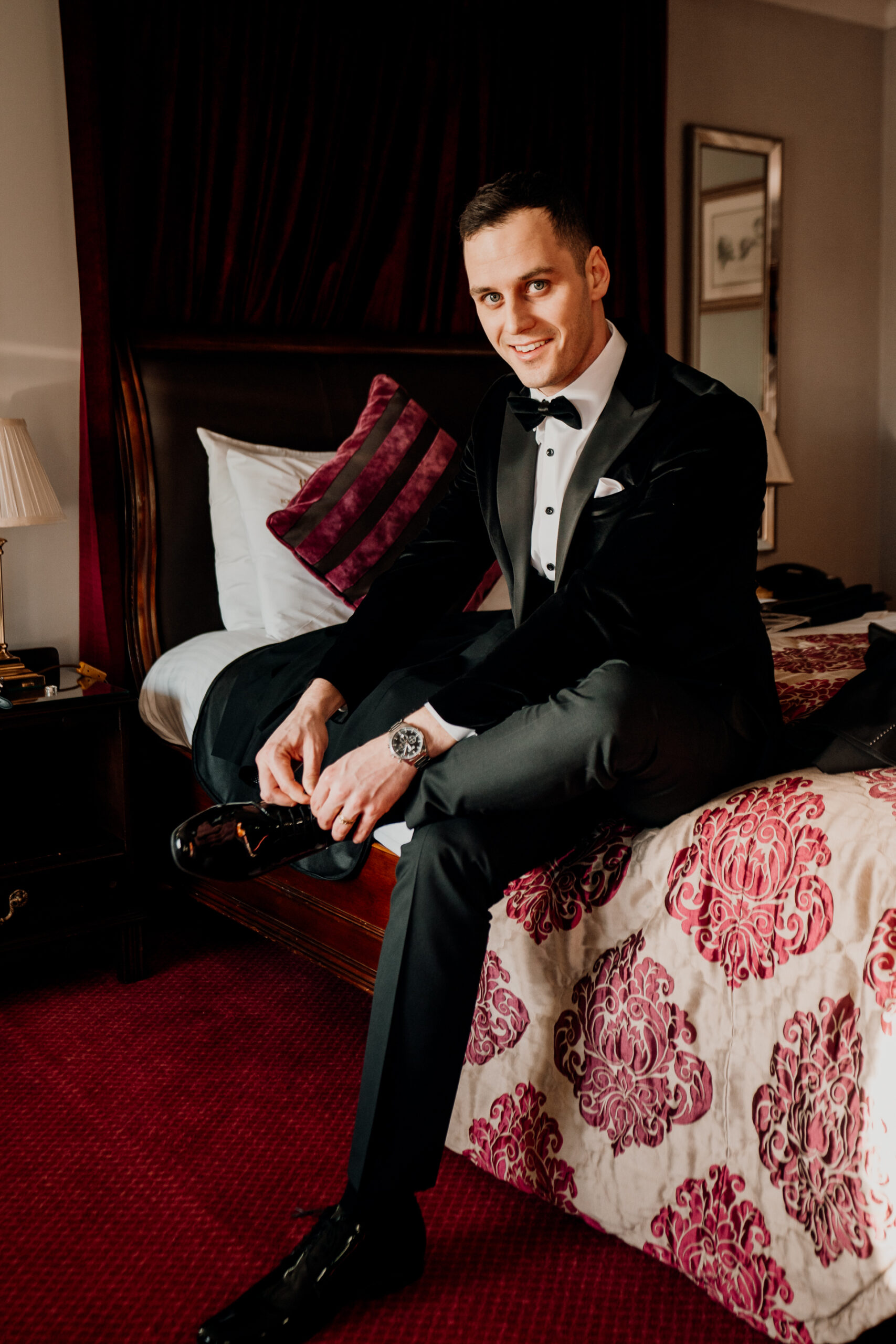 A person in a tuxedo sitting on a bed