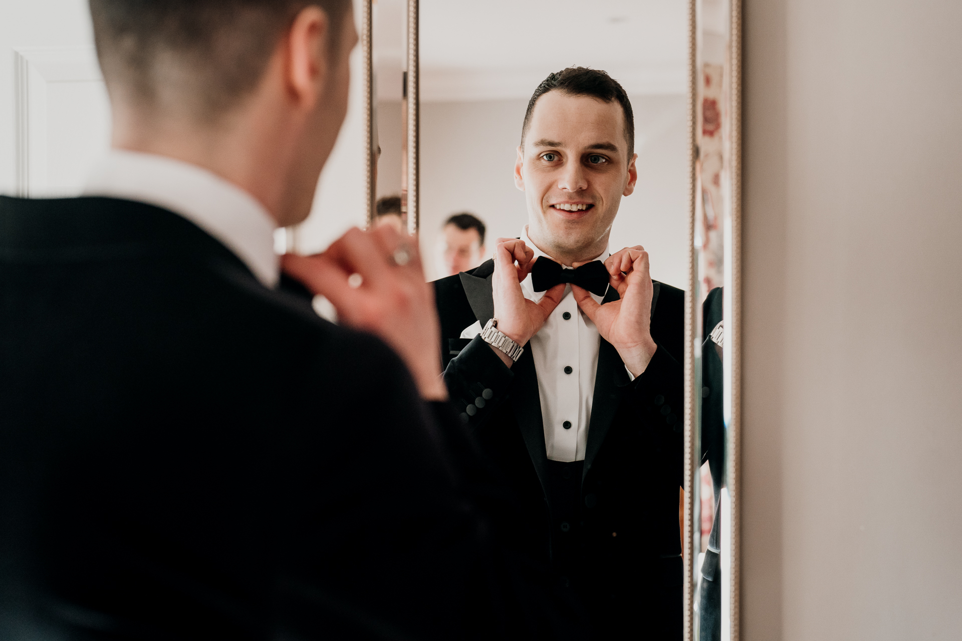 A man in a tuxedo adjusting his tie