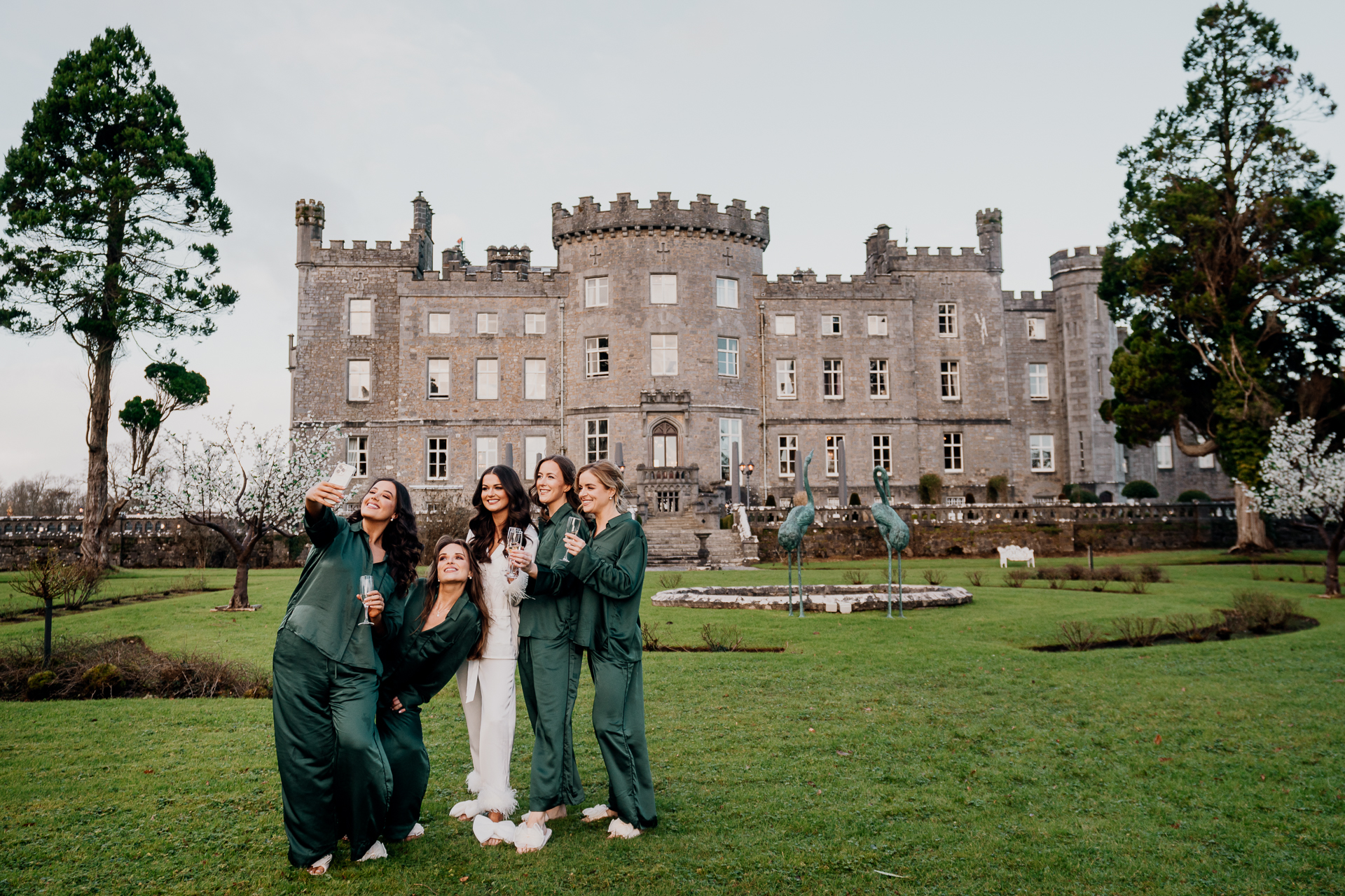 A group of people in green robes in front of a large building