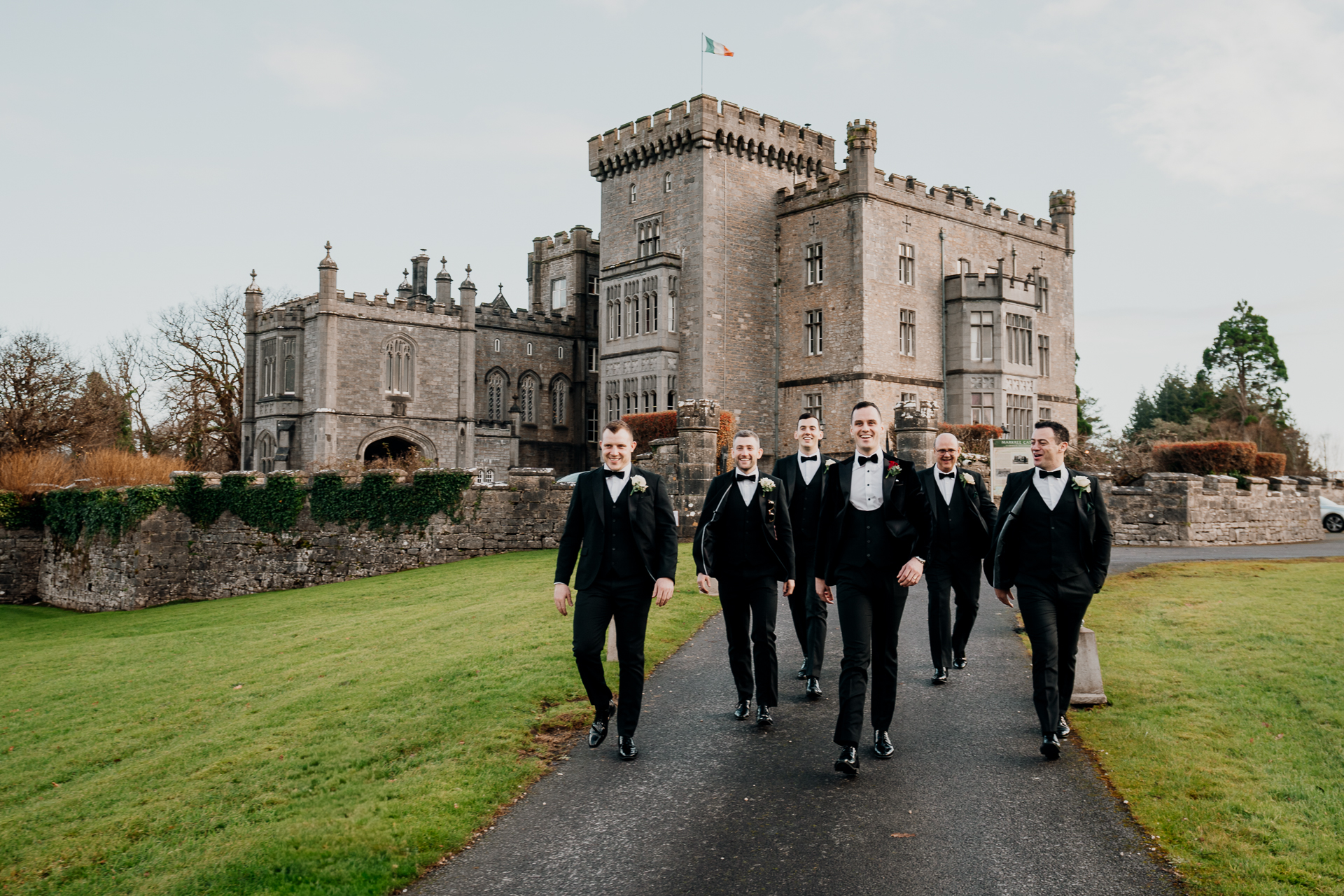 A group of men walking down a path in front of a castle