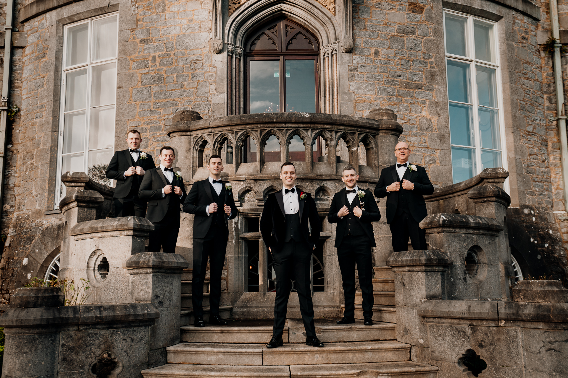 A group of men in suits standing on stairs in front of a brick building