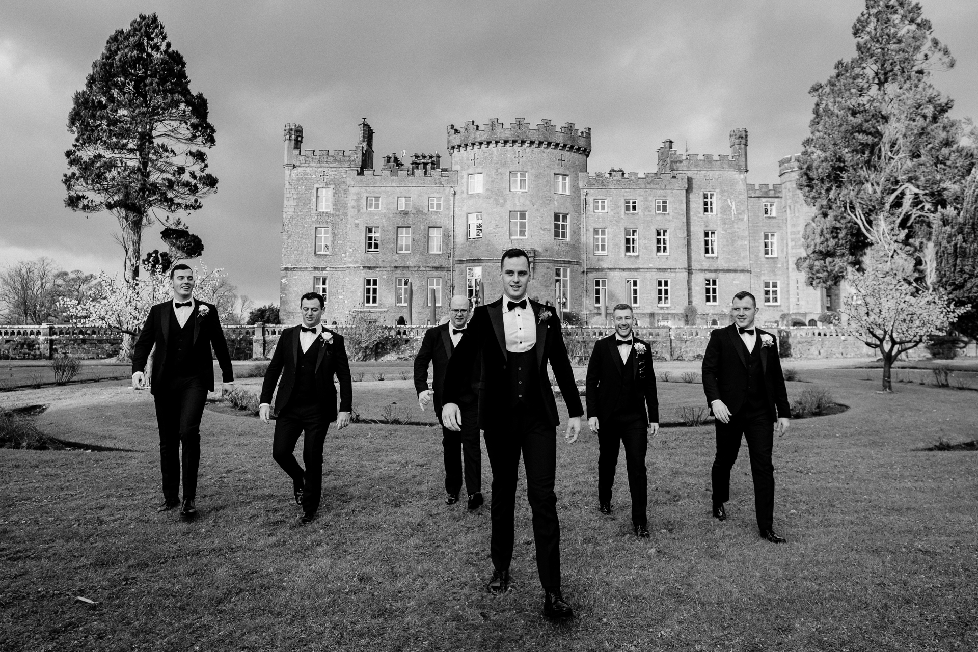 A group of men in suits walking in front of a large building