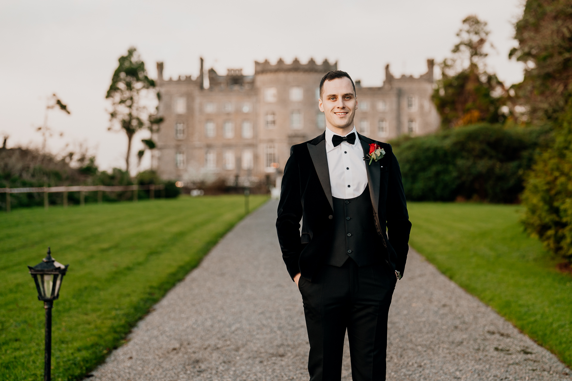 A person in a tuxedo on a path in front of a large building