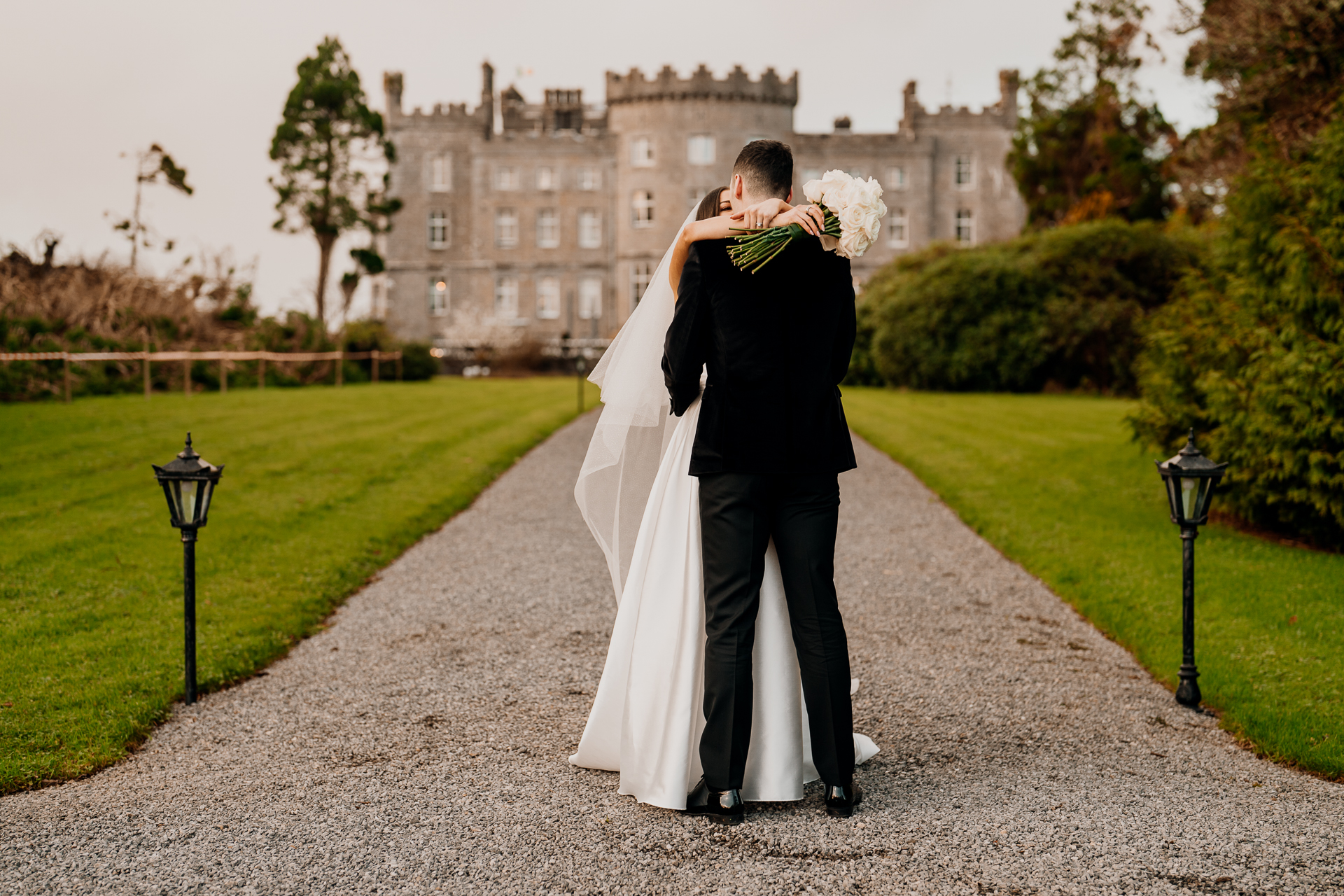 A man and woman kissing in front of a large building