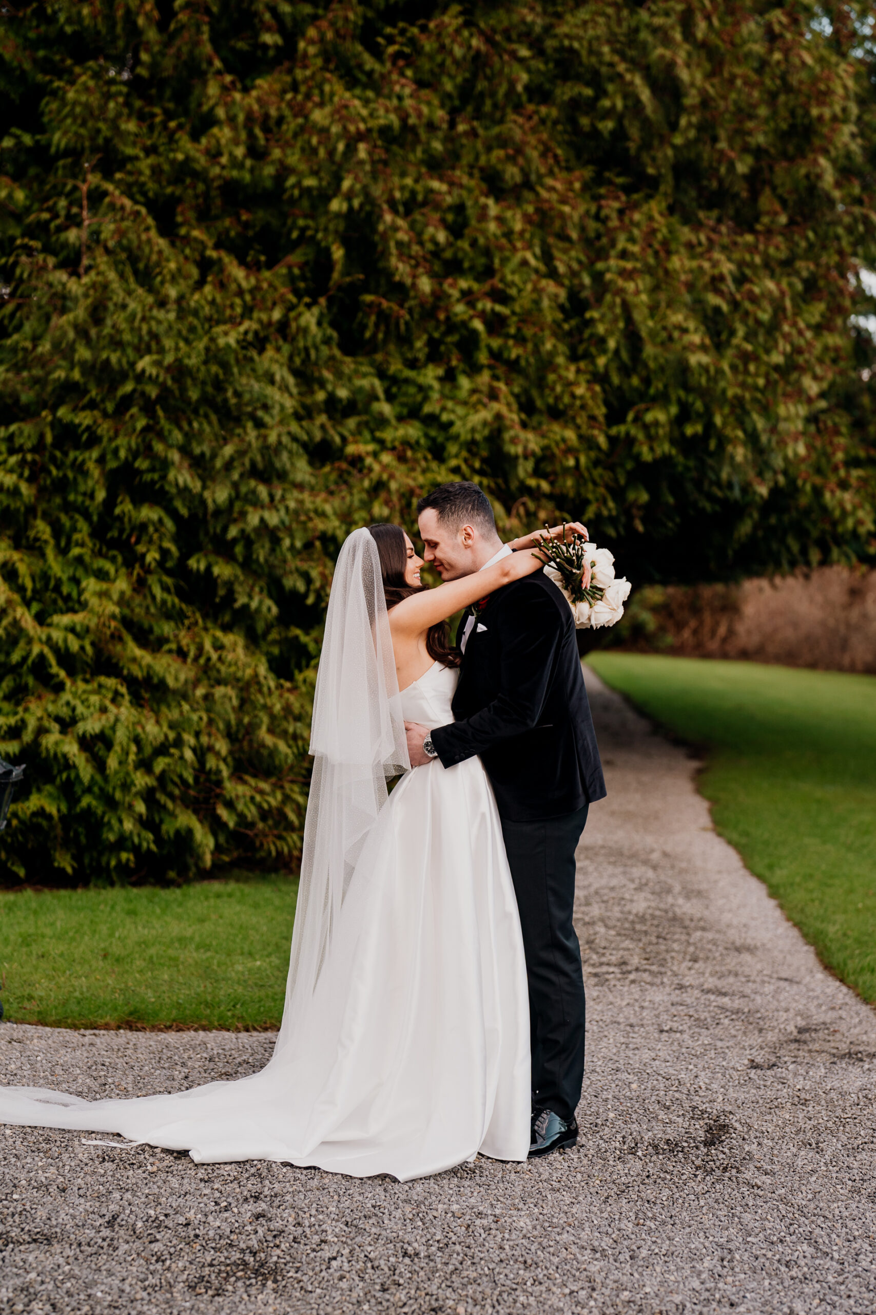 A man and woman kissing on a road with trees in the background