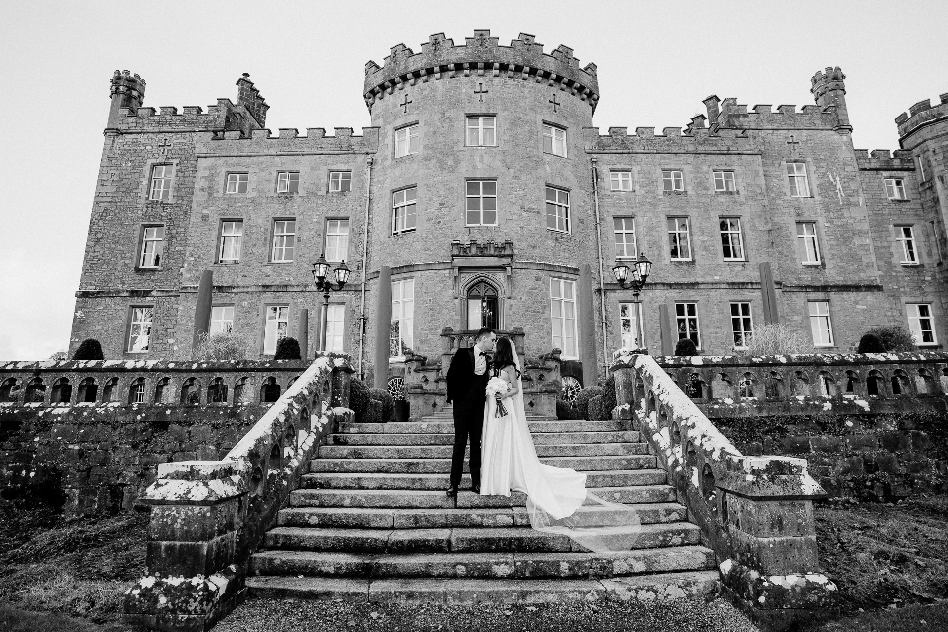 A man and woman kissing on stairs in front of a large building