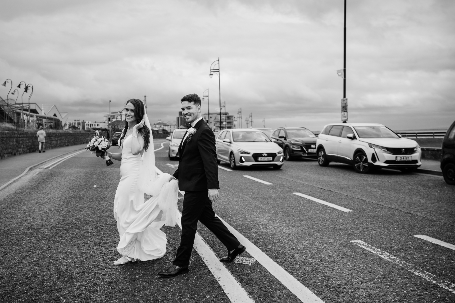 A man and woman walking down a street with cars on the side