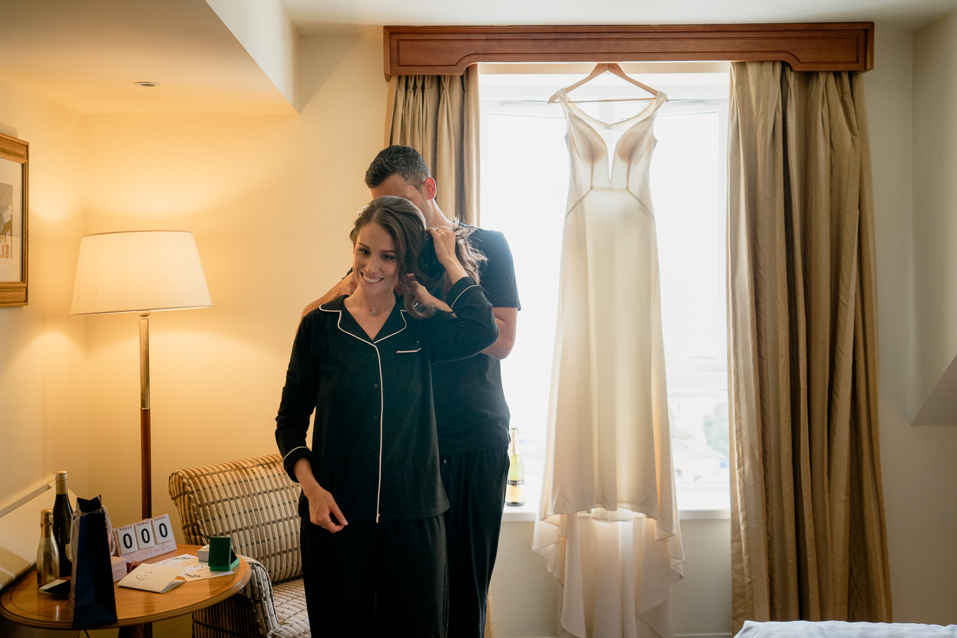 A man and woman kissing in a room with a window and curtains