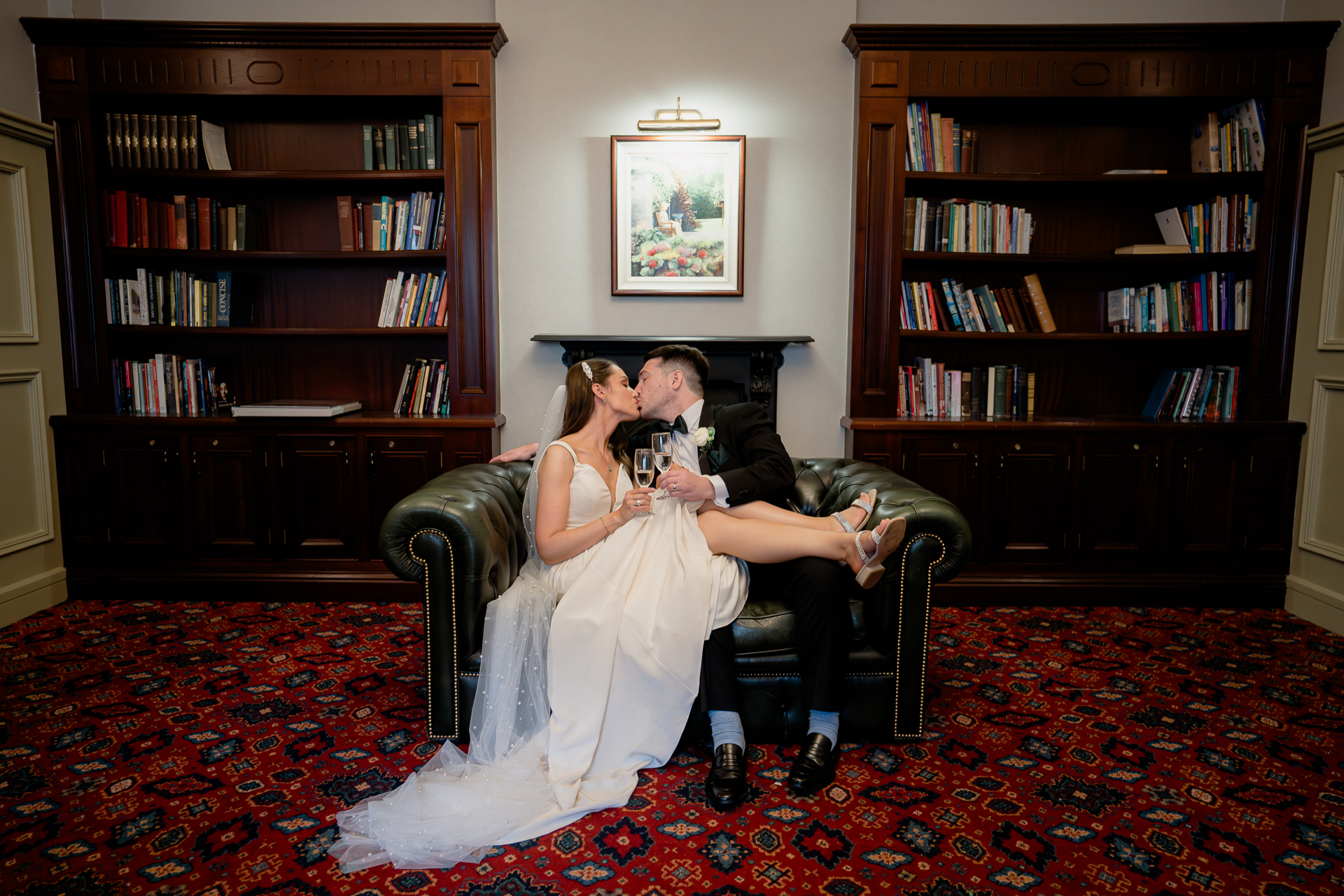 A man and woman sitting on a couch in a room with a bookcase and a book shelf