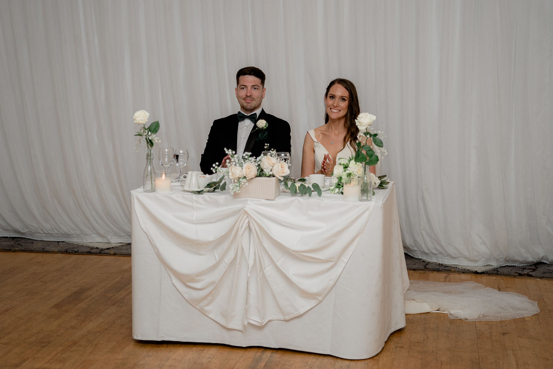 A bride and groom sitting at a table with flowers