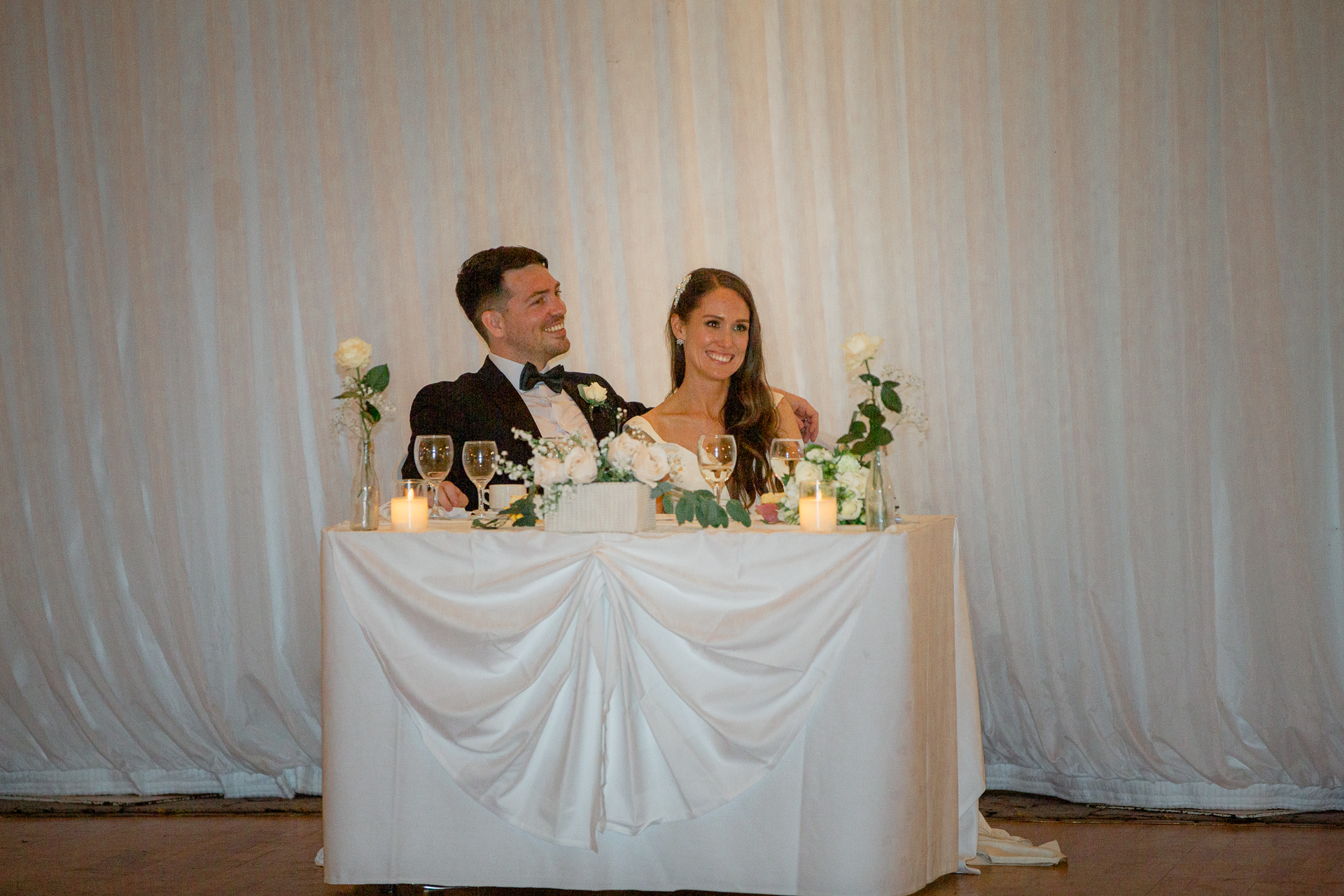 A man and woman sitting at a table with flowers and candles