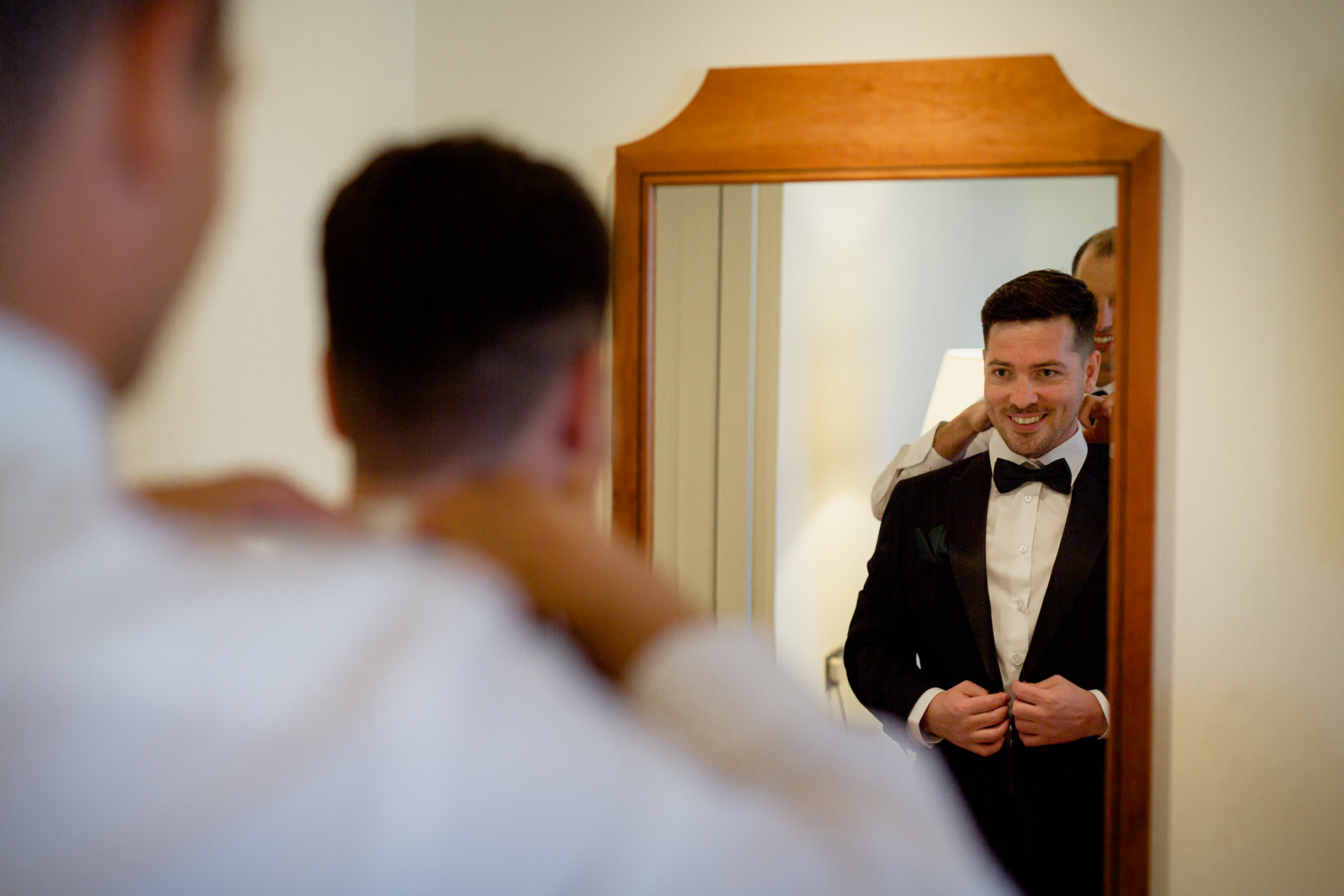 A man in a tuxedo looking at a mirror