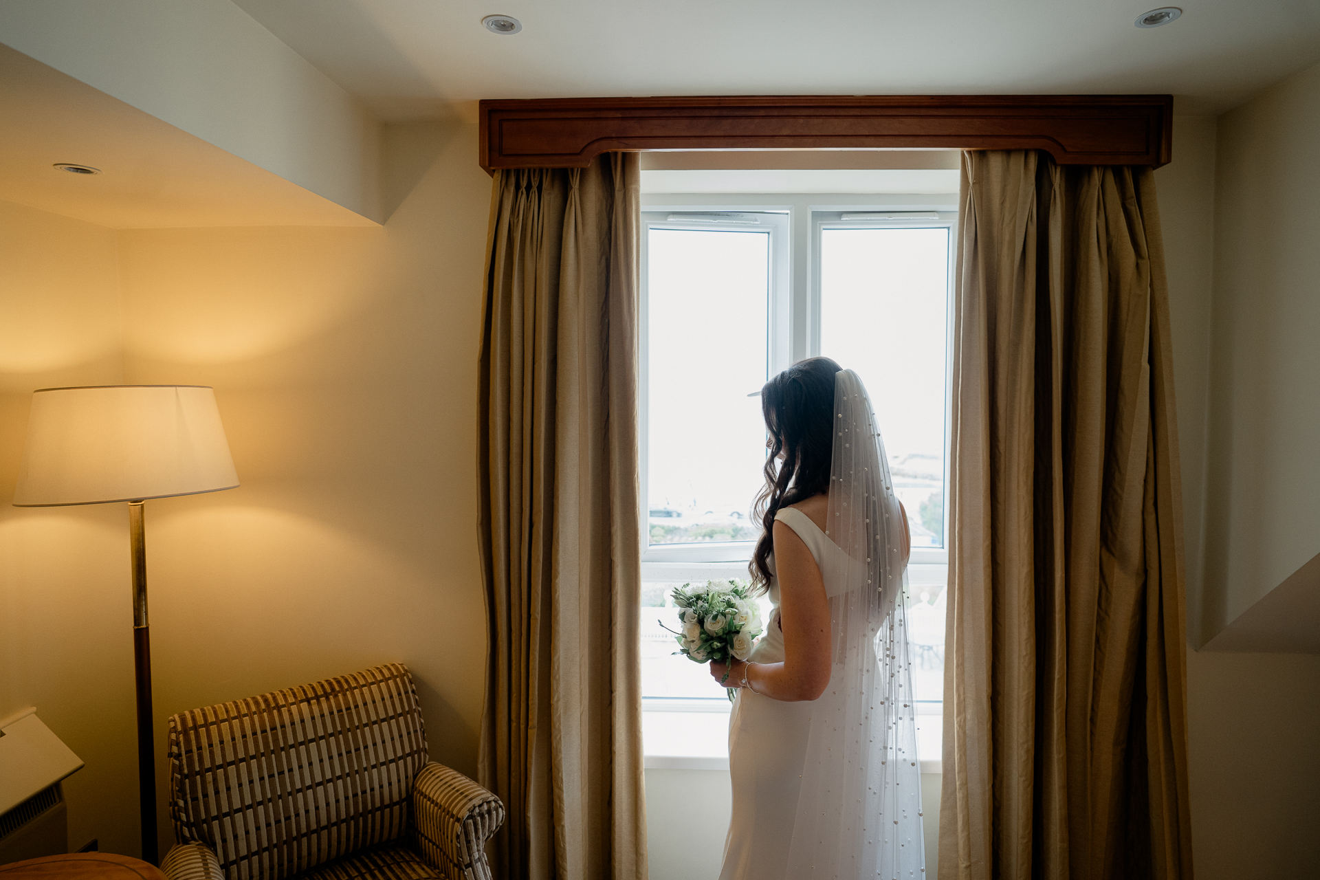 A person in a white dress looking out a window