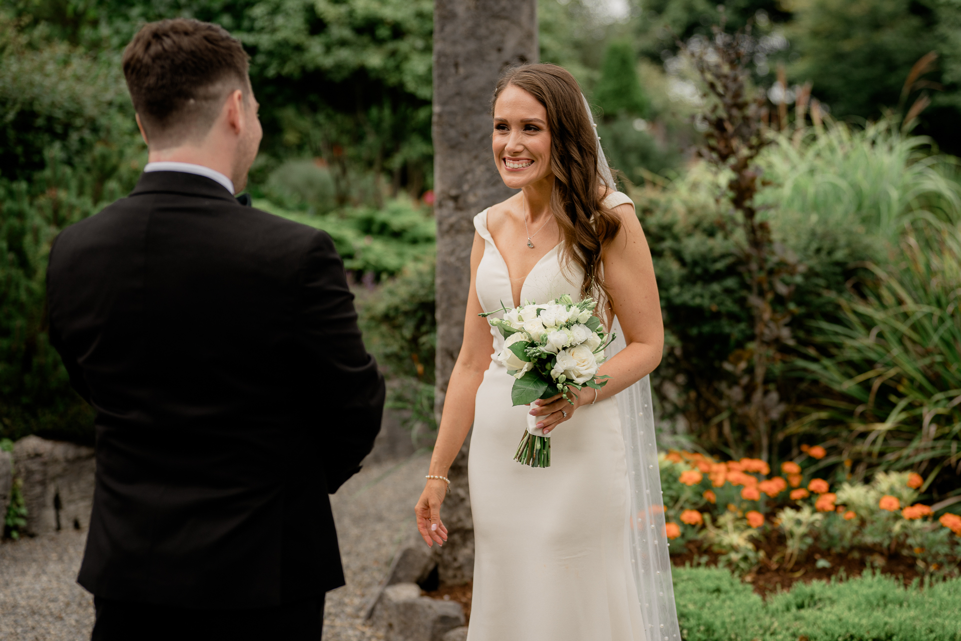 A man and woman walking down a path with flowers and trees