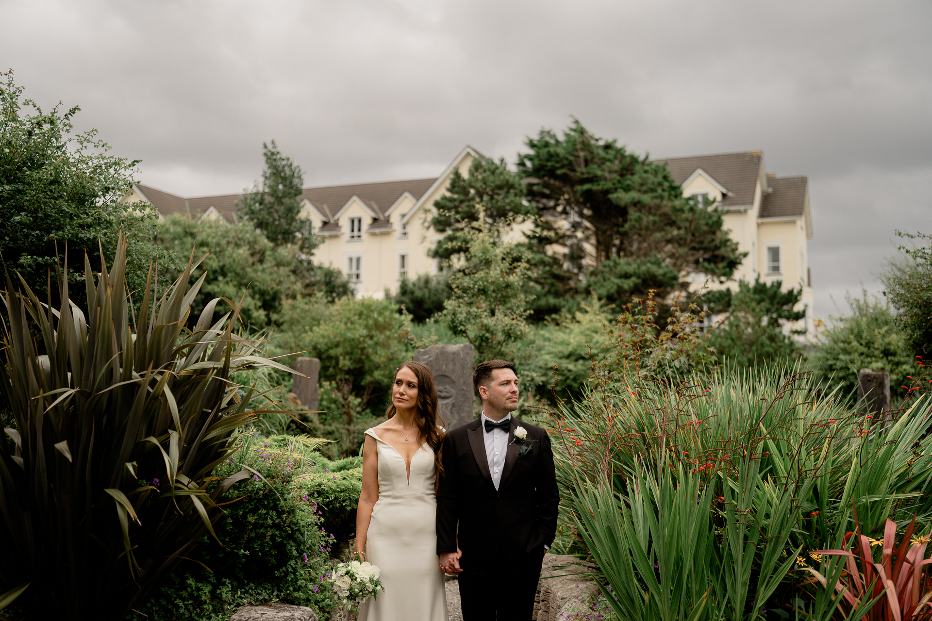 A man and woman posing for a picture in front of a garden