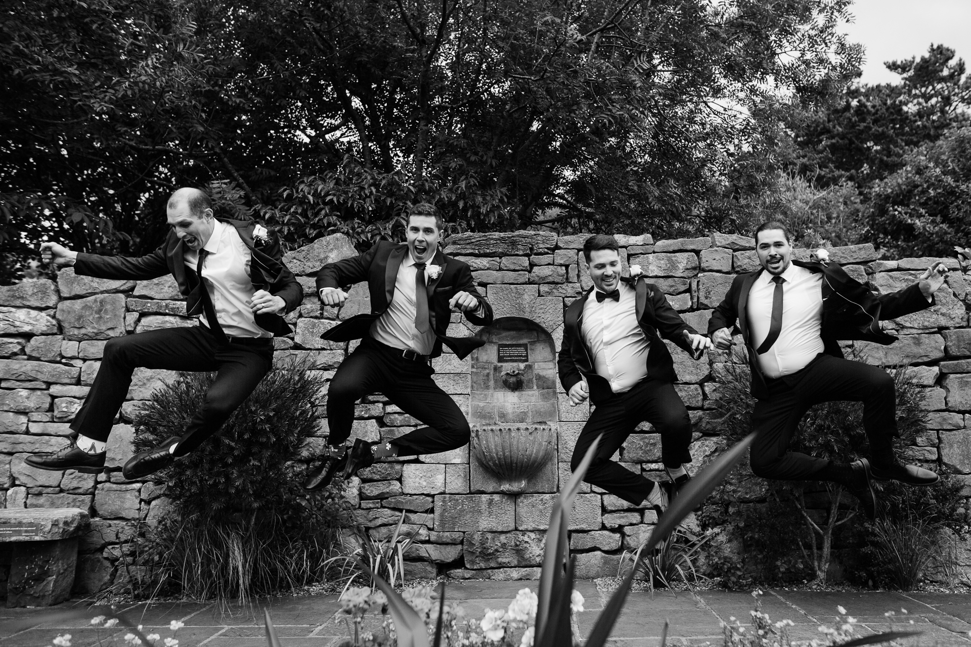 A group of men jumping on a stone wall