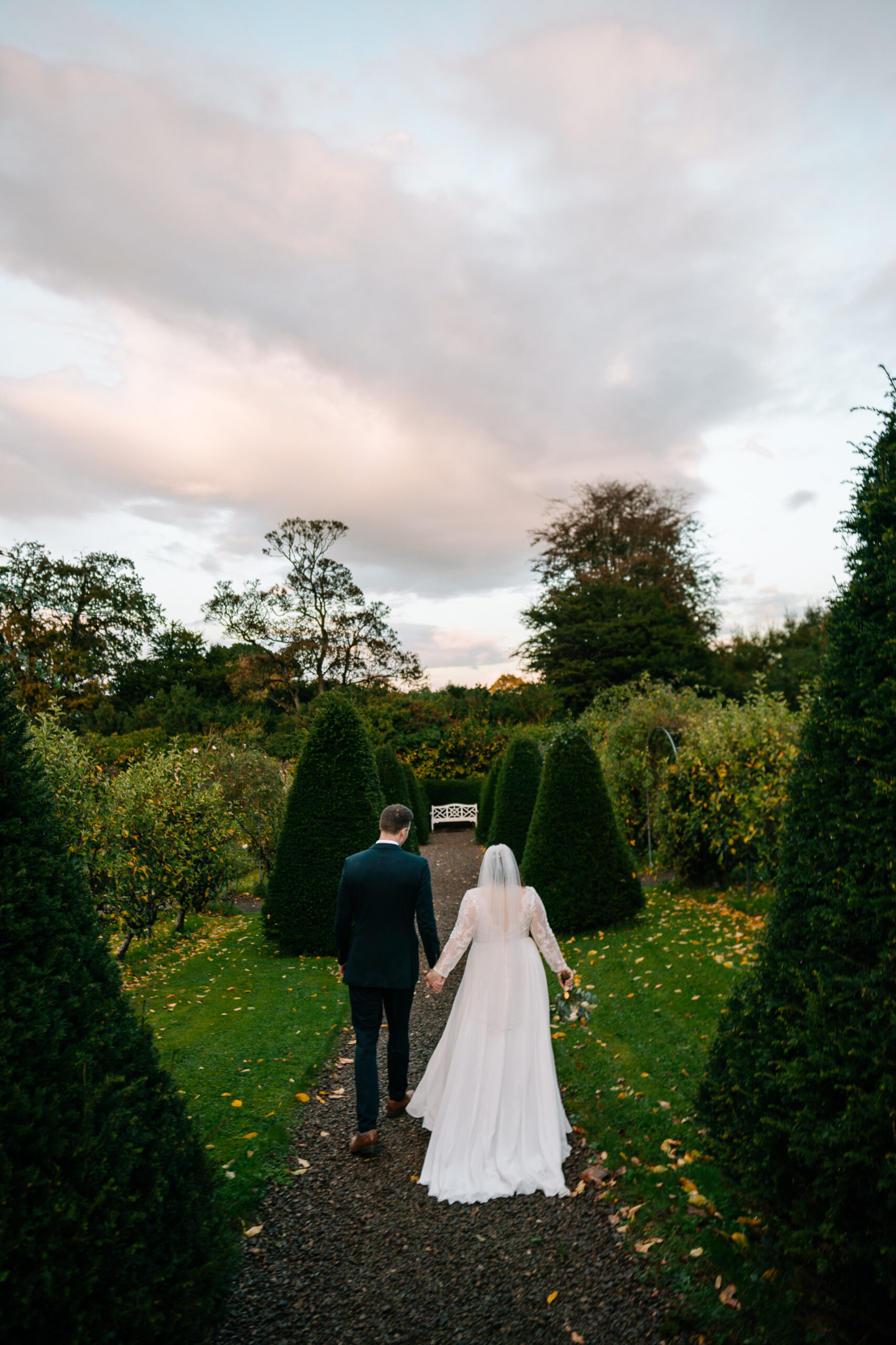 A man and woman walking down a path in a garden