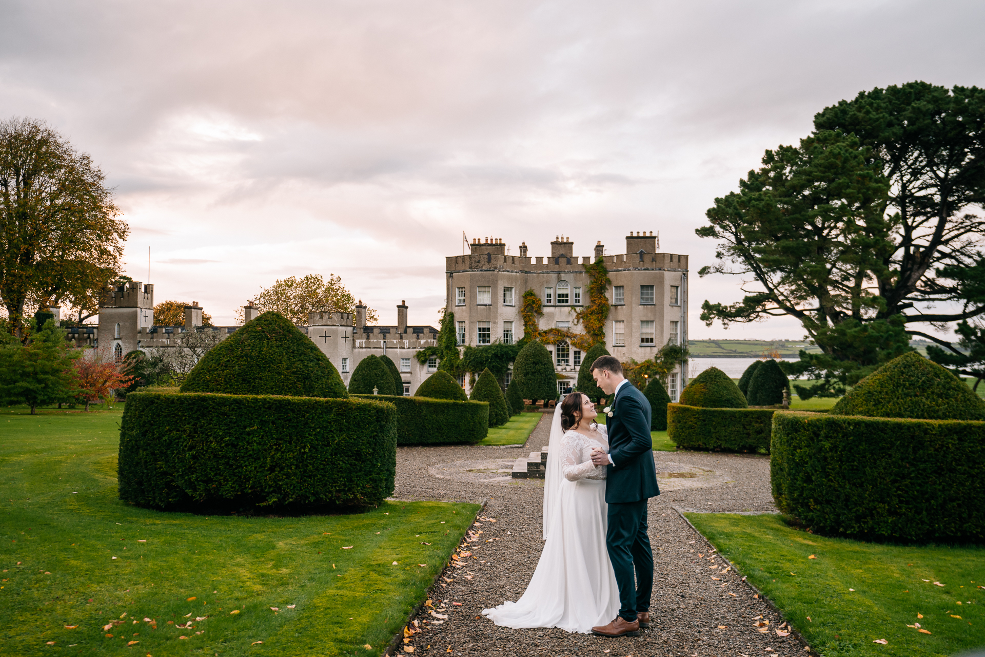 A man and woman in wedding attire kissing in front of a large building