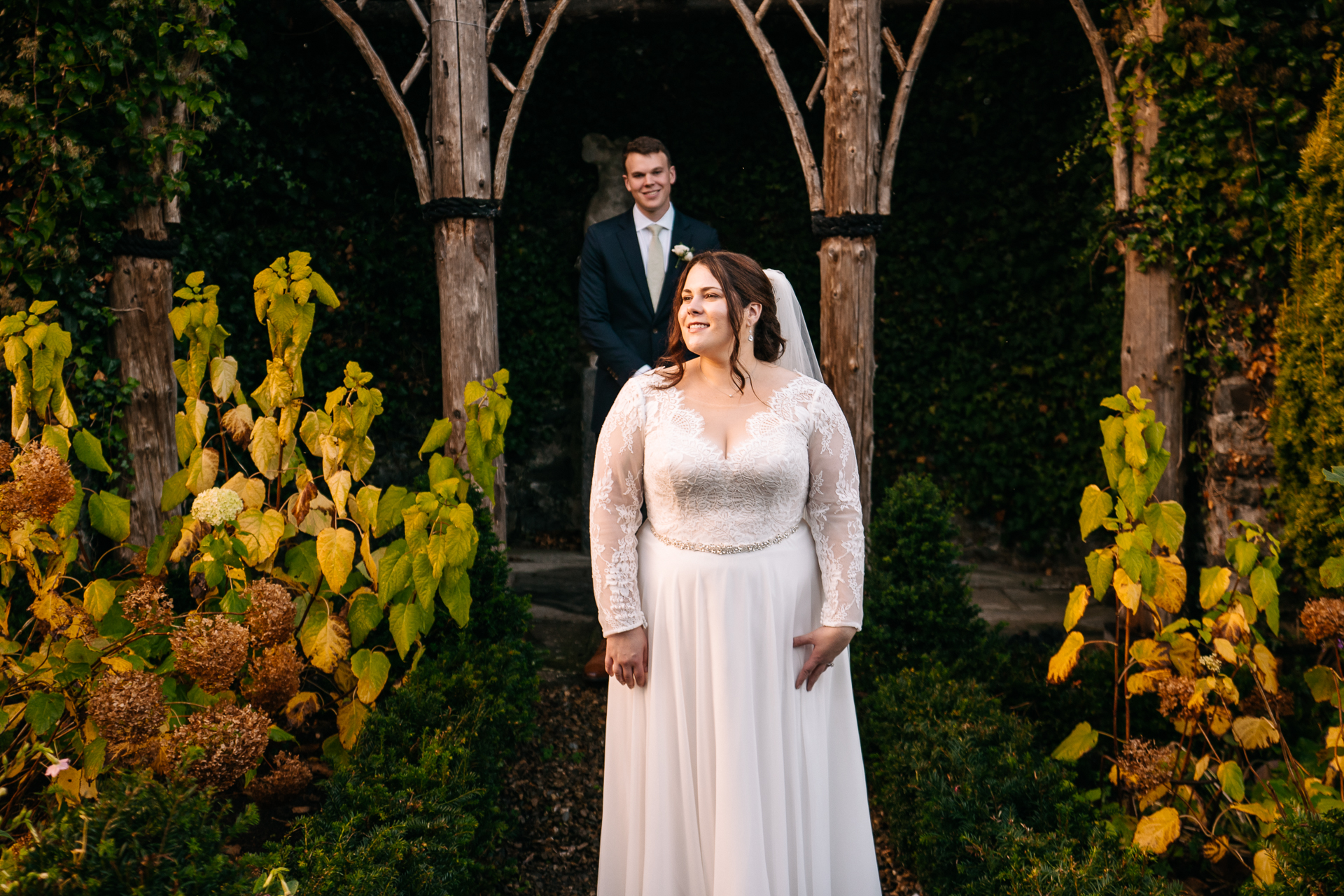 A man and woman in wedding attire standing in a forest