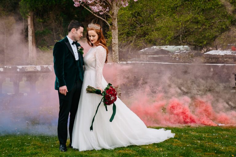 Bride and groom at Markree Castle surrounded by pink and red smoke, styled with a royal crown and red roses. Perfect portrait for showcasing Markree Castle wedding cost and luxury feel.
