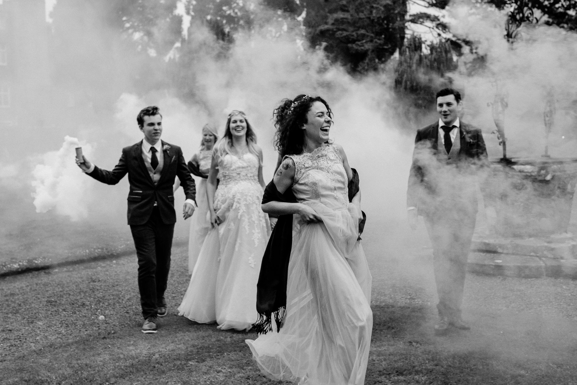 Bride laughing with her wedding party surrounded by smoke at Markree Castle garden