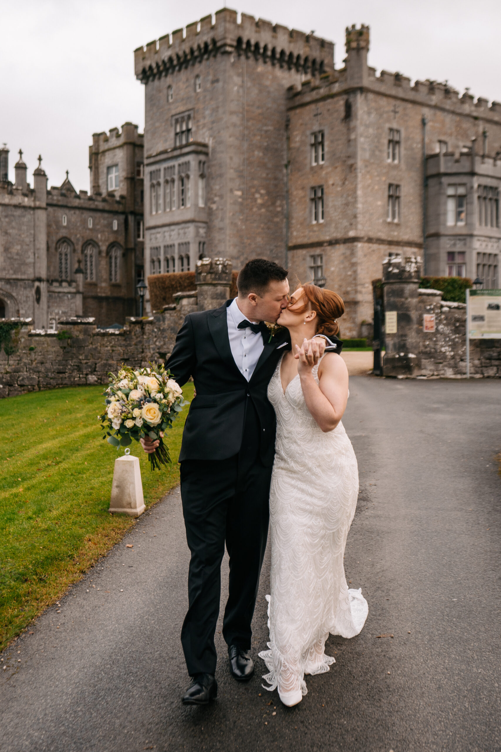 A man and woman kissing in front of a castle