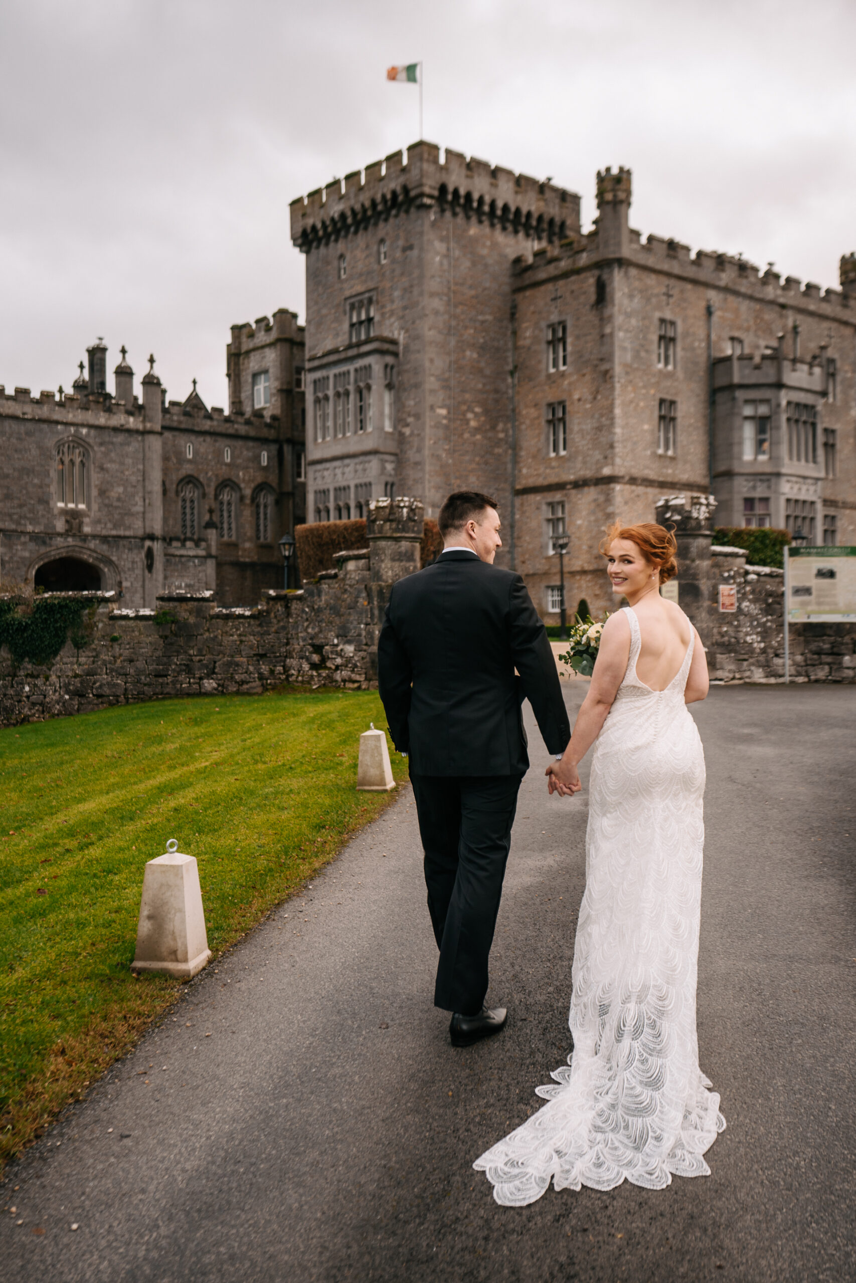 A man and woman walking down a path in front of a castle