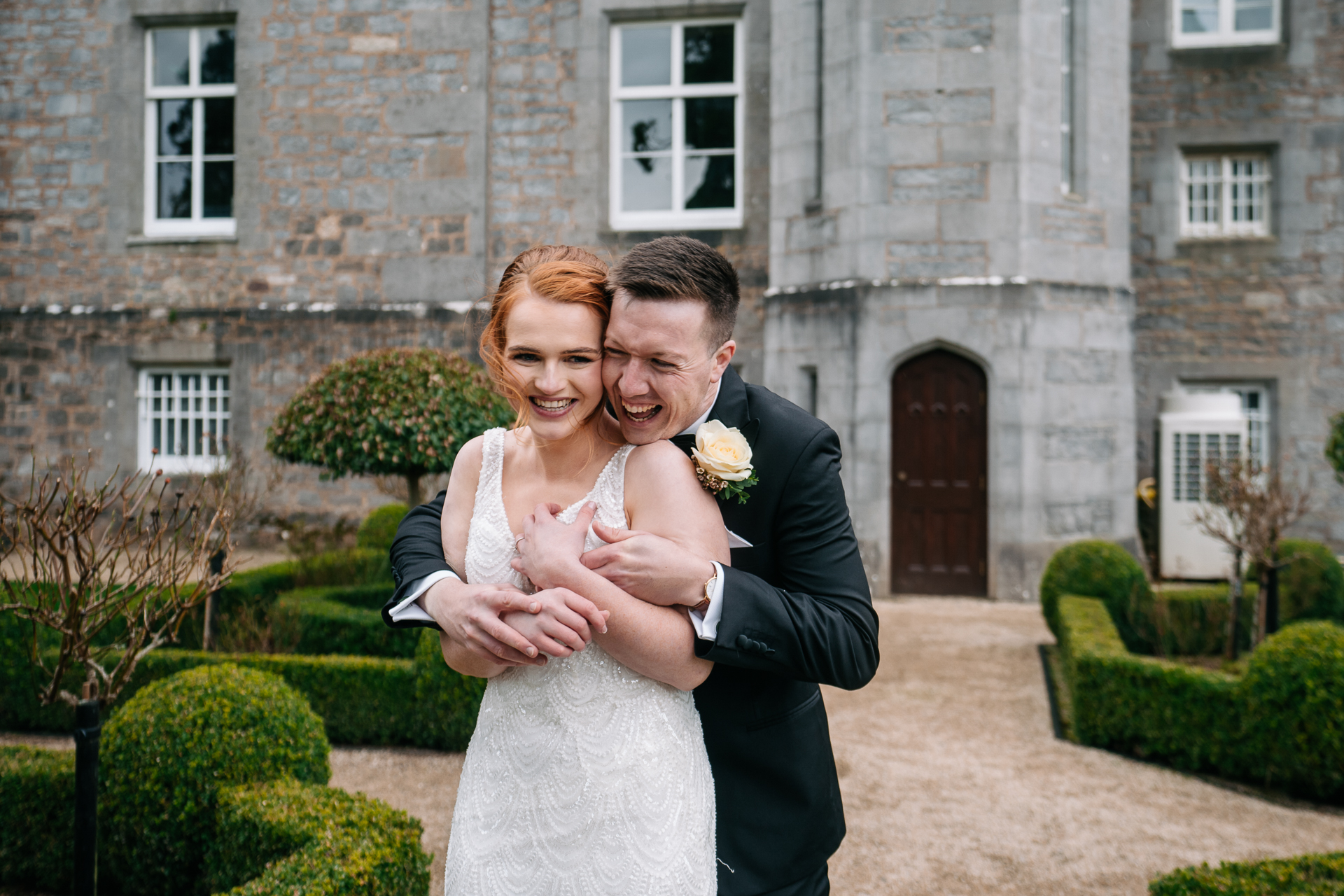 A man and woman posing for a picture outside of a stone building