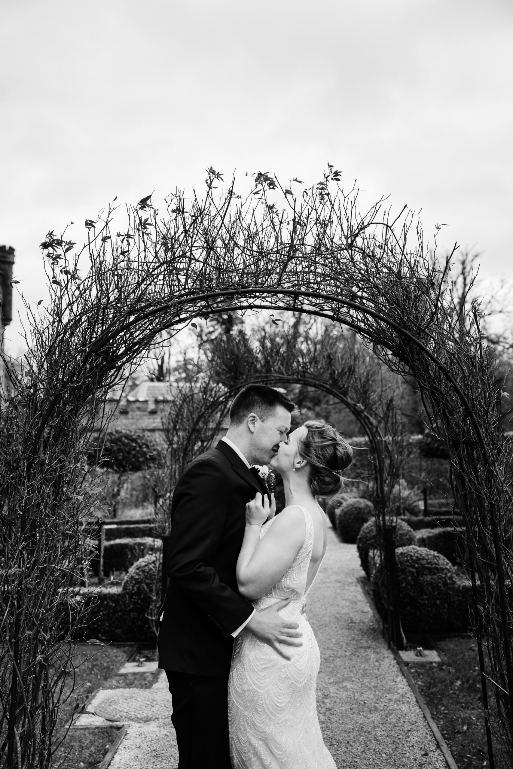 A man and woman kissing in front of a large arch