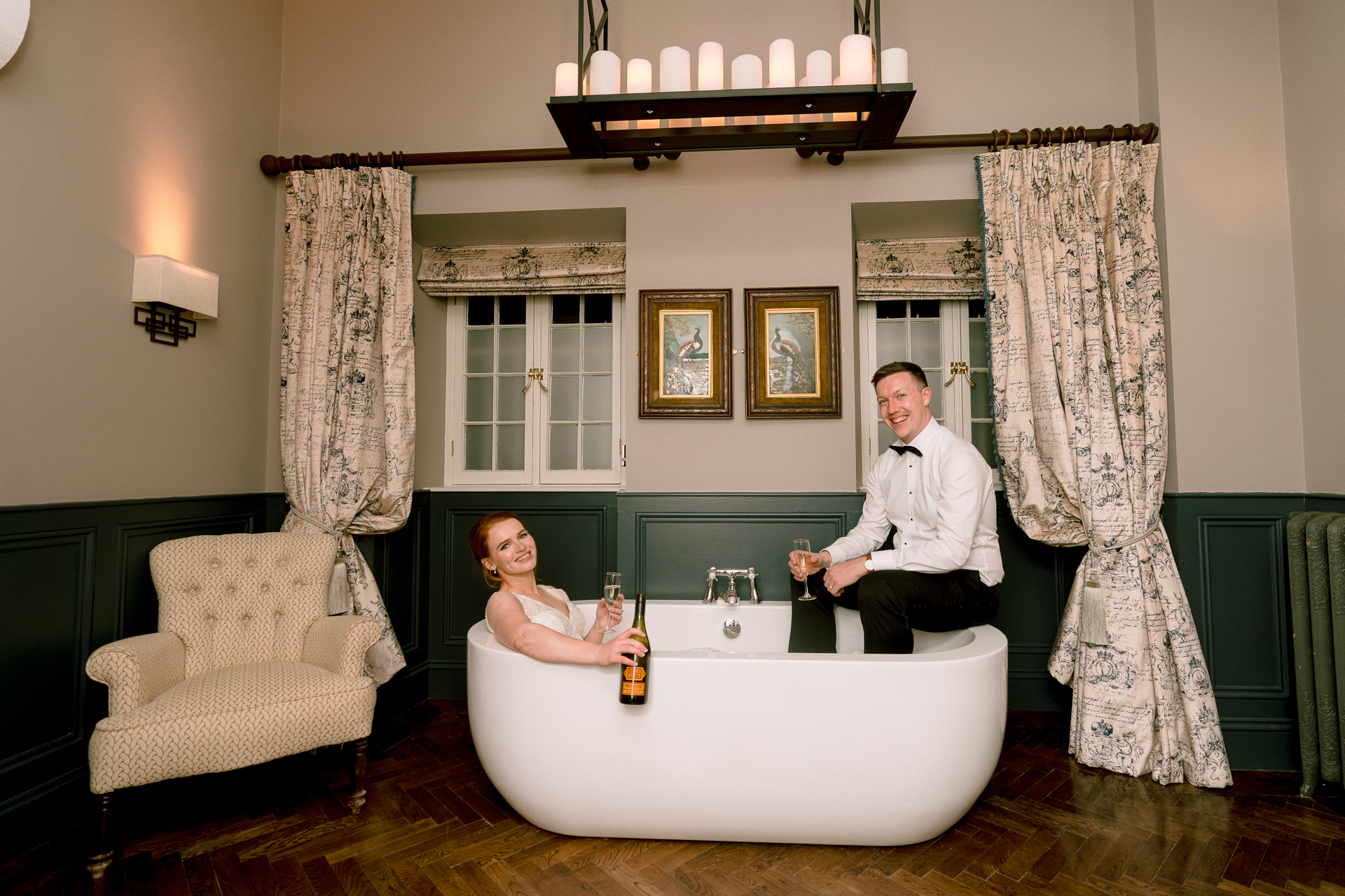 A man and woman sitting at a table in a room with a large white tub and chandel