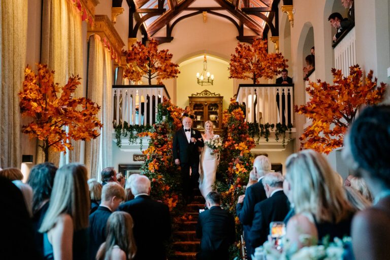 Wedding ceremony at Dromoland Castle with an aisle beautifully decorated with warm autumn colors.
