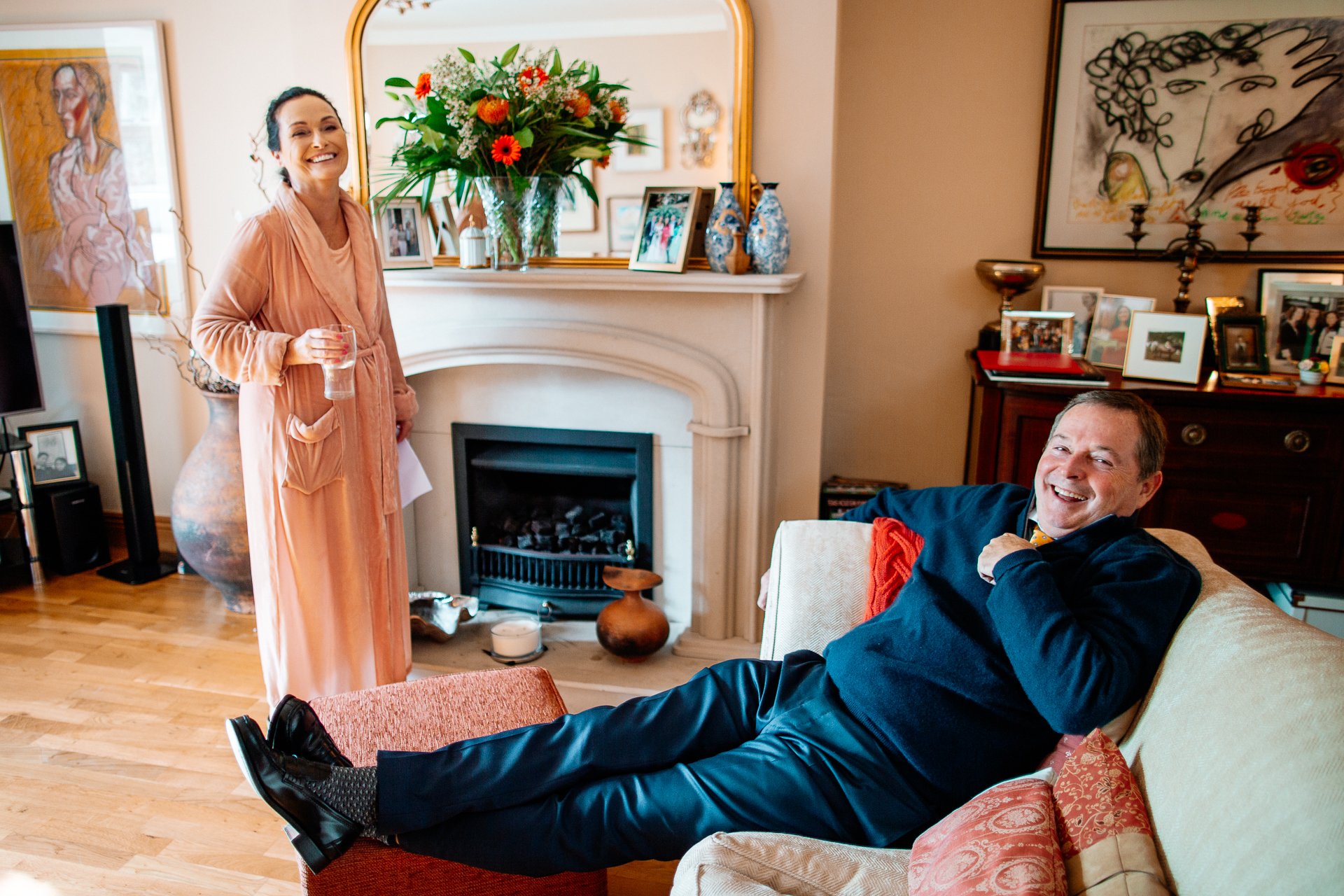 A man sitting on a couch with a woman standing behind him