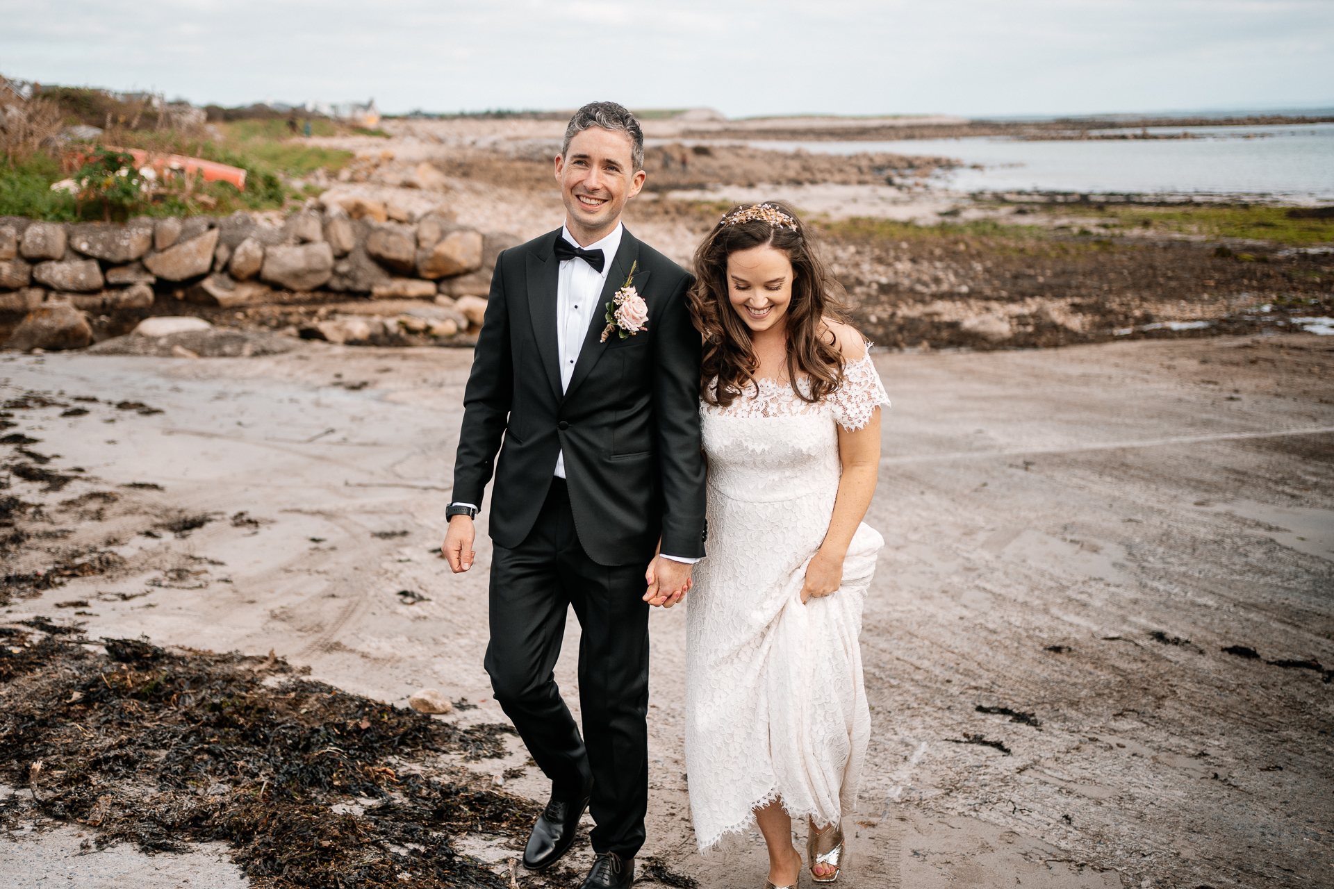 A man and woman in wedding attire walking on a beach