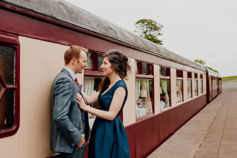 Newlyweds sharing a romantic moment by the historic Pullman train at Glenlo Abbey Hotel wedding.