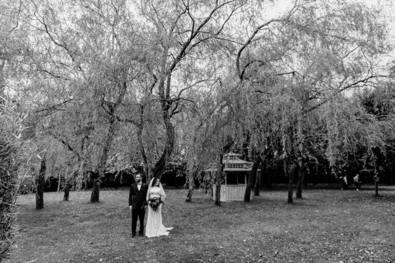 Text: Bride and groom in the beautiful gardens of Barberstown Castle, captured in an elegant and timeless moment.
